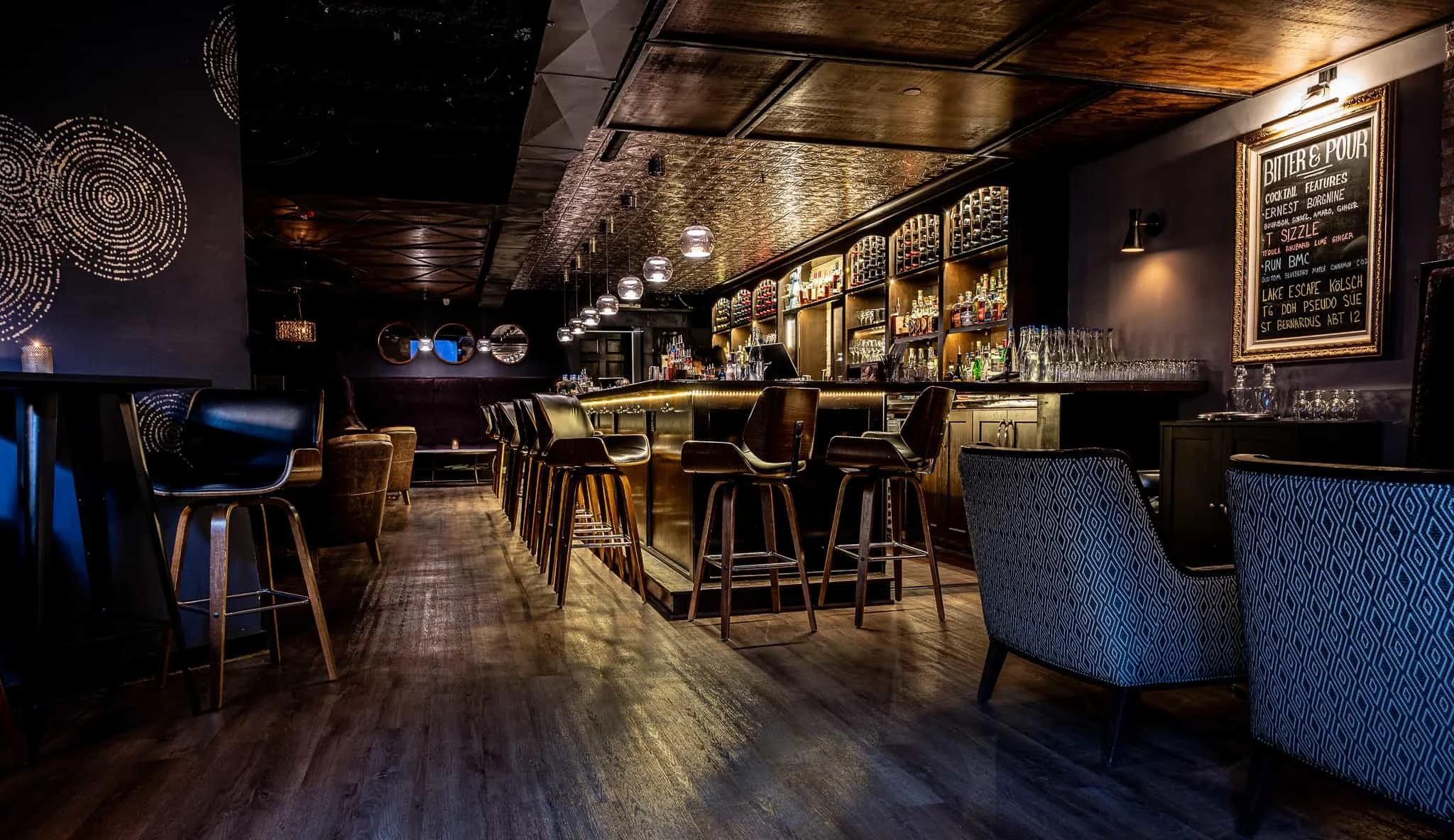 Indoor restaurant bar area with a circular counter, warm lighting, and signs indicating food and drink options, including chicken and orders here.
