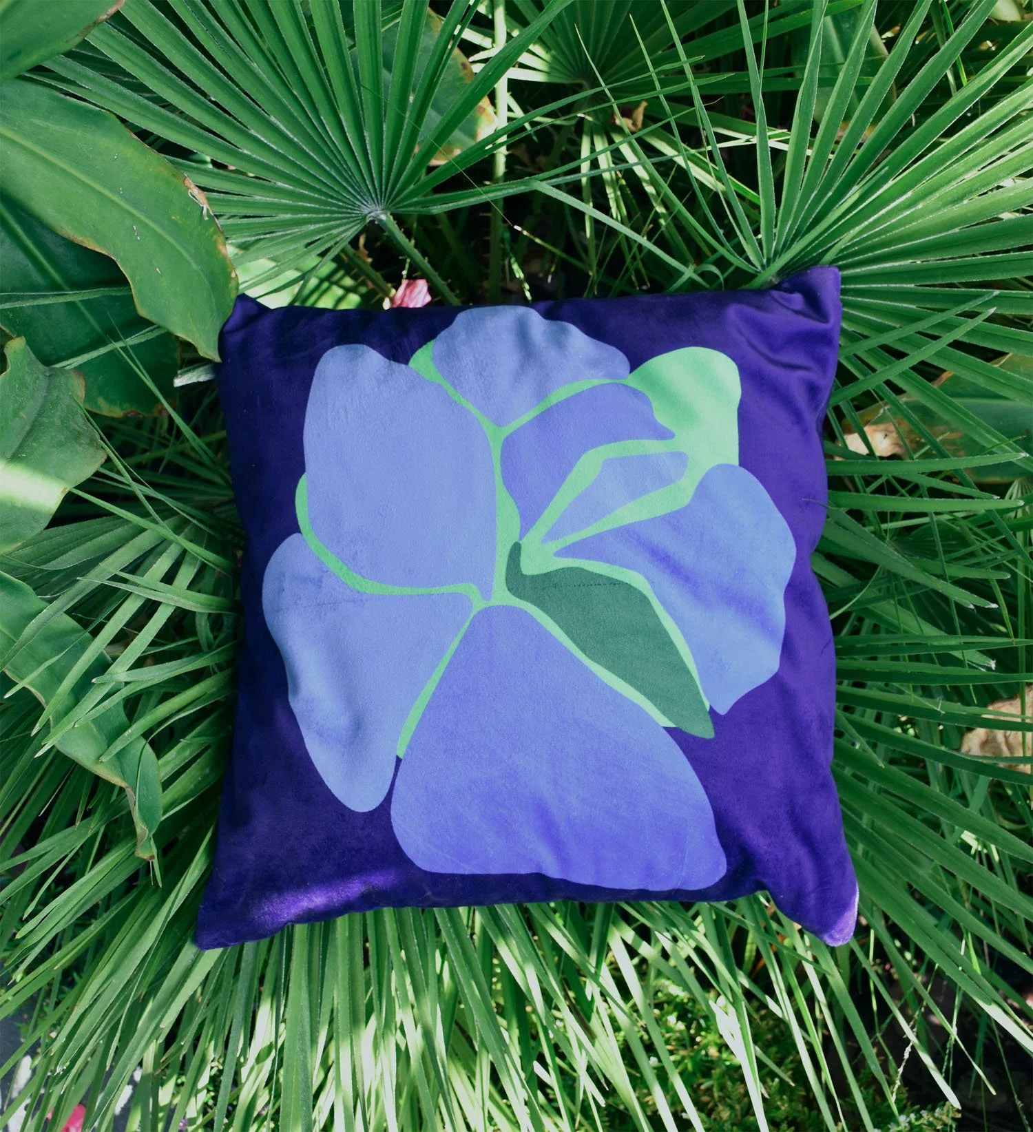 Cushion cover with single big Pansy flower in blue and green, photographed on palm leaves in Madeira — by Kaisa Valtakari