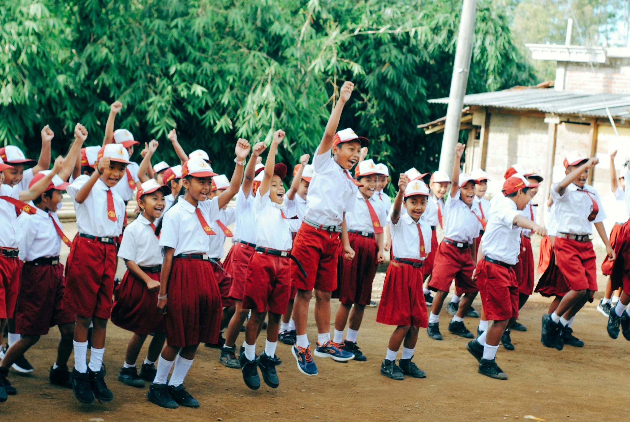 Group of school children in uniform jumping and playing outdoors.