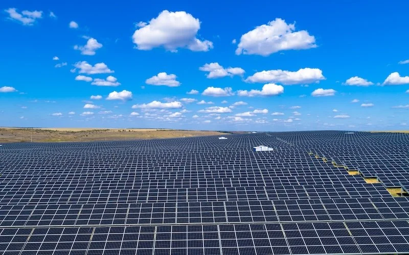 Solar panels off into the distance below a blue sky