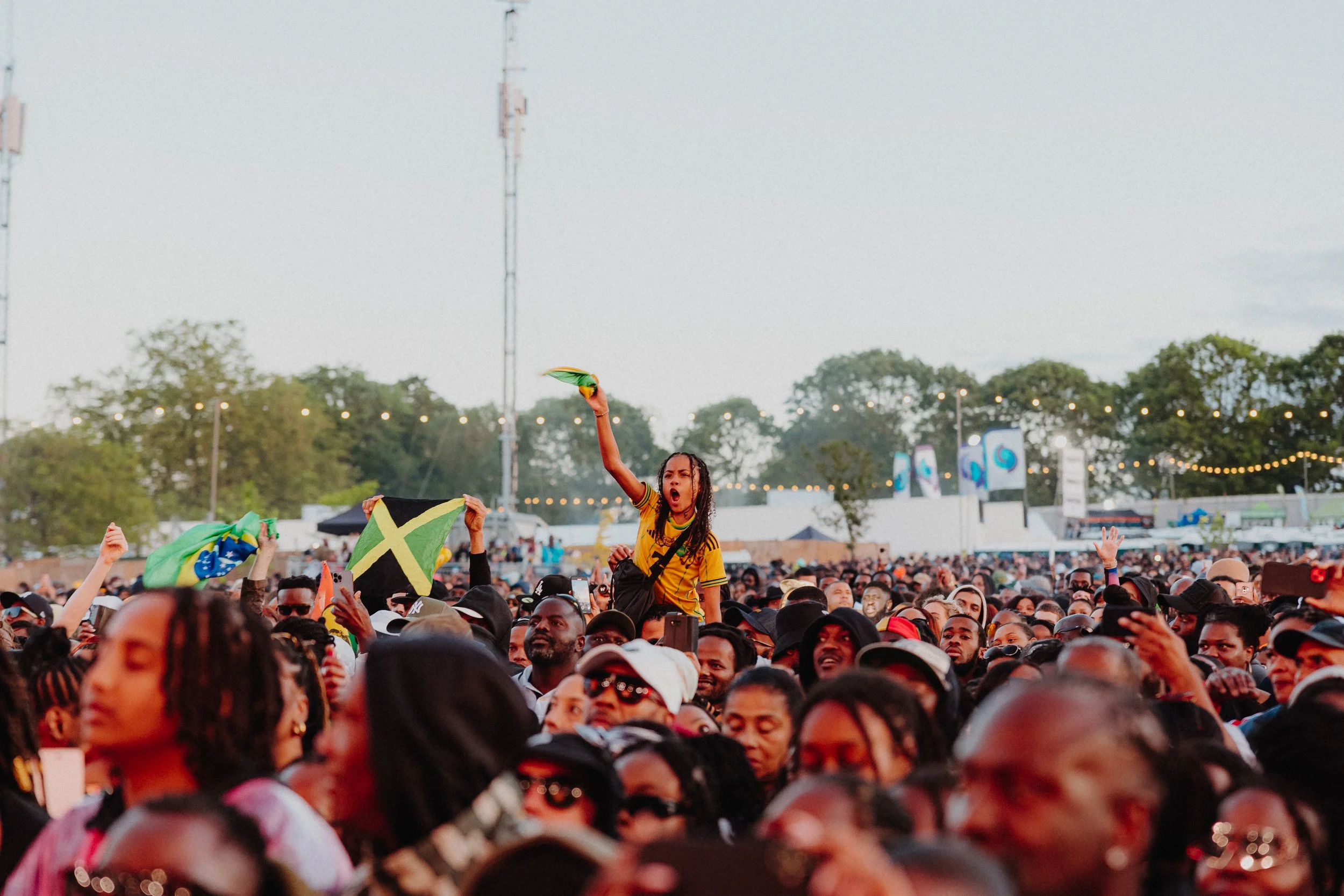 a boy in a festival crowd waving a Jamaican flag