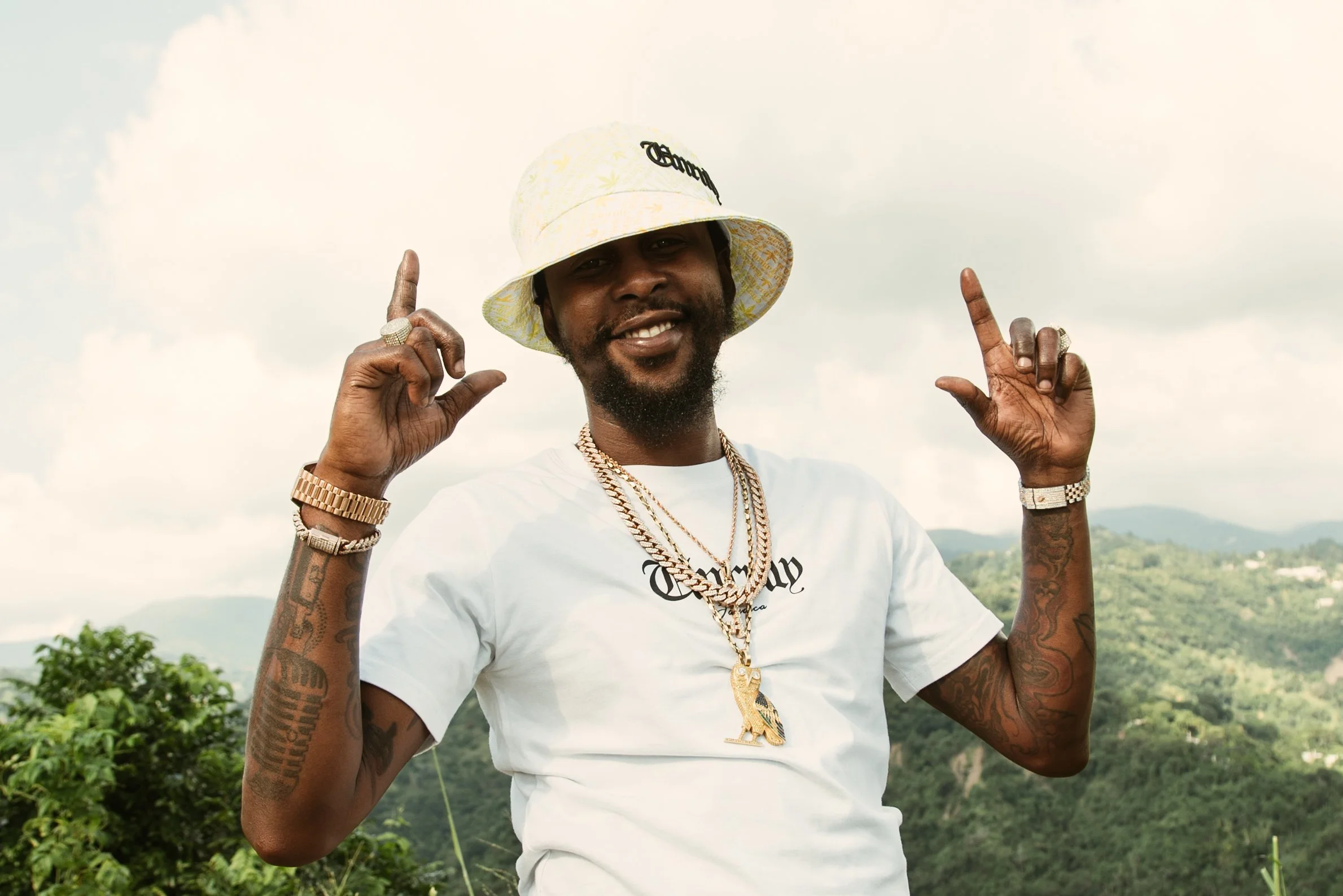 Dancehall artist Popcorn smiles in front of the beautiful countryside