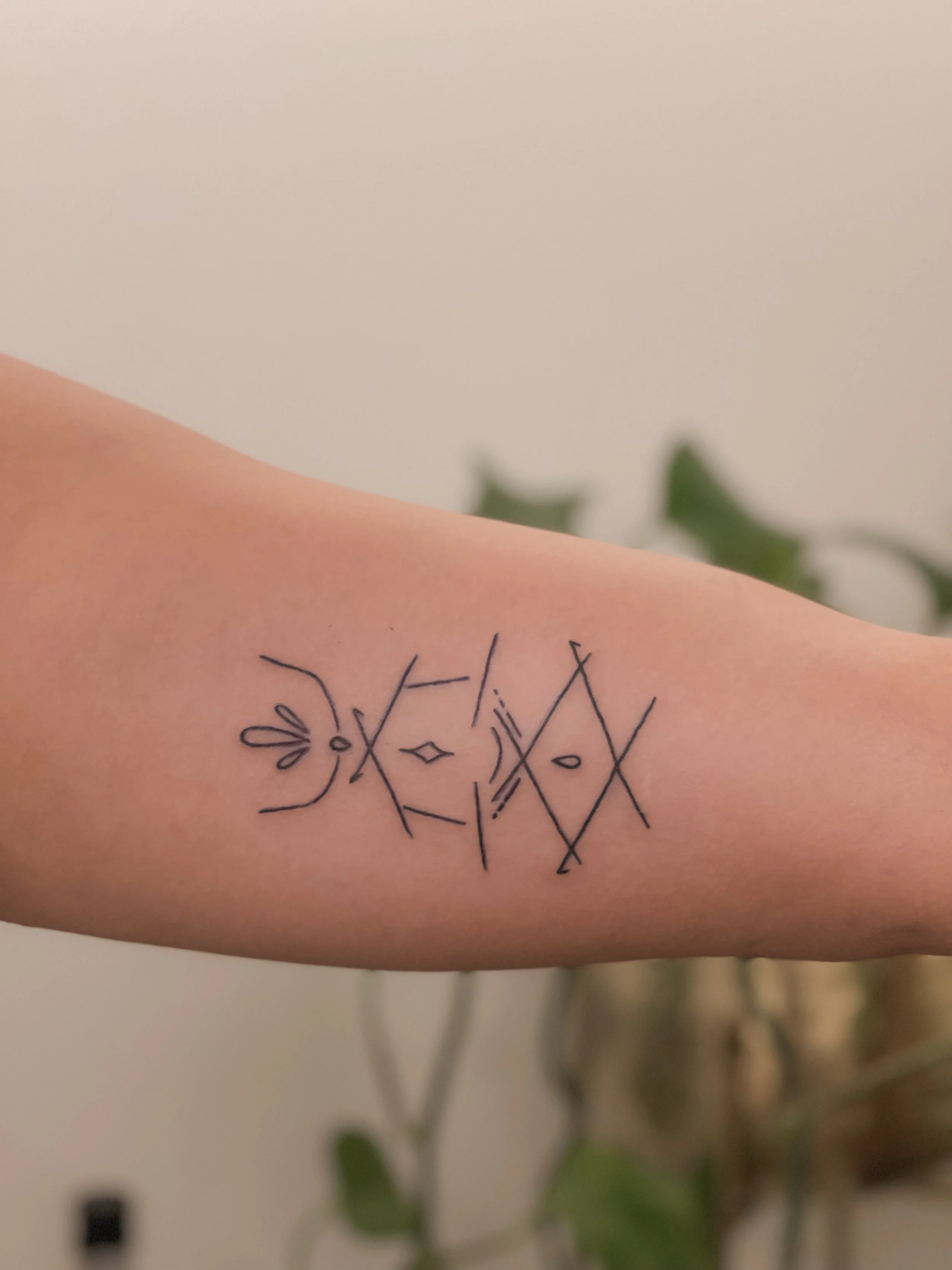 Tattoo of abstract geometric shapes and lines on a person's inner forearm.