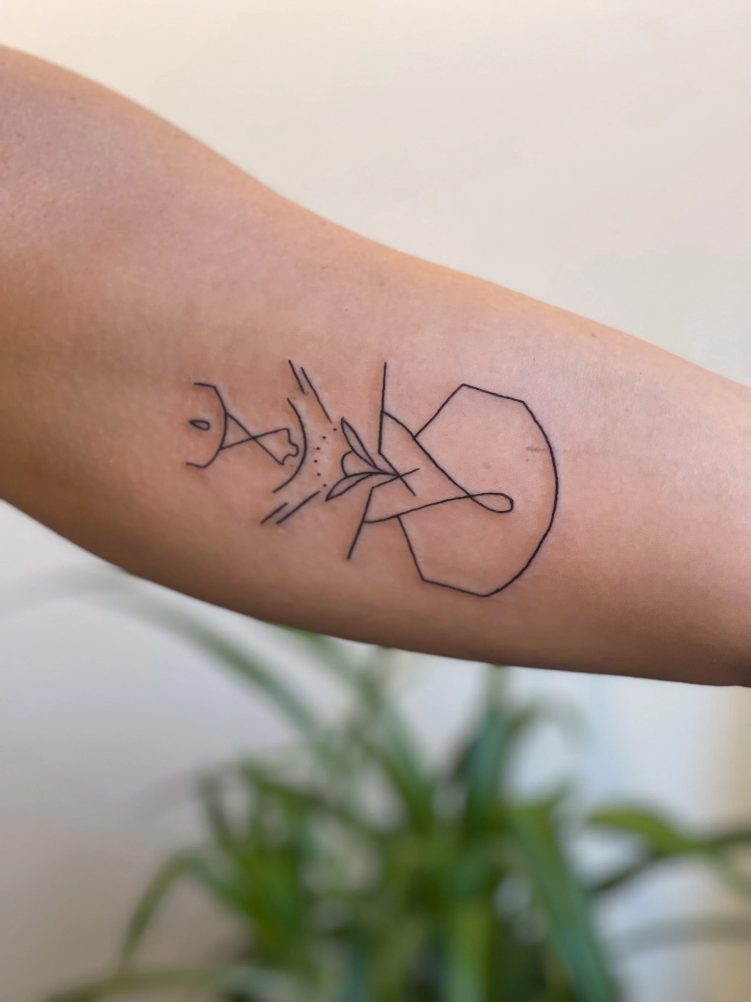 Minimalist tattoo of a person playing guitar with a microphone stand, drawn with simple black lines on a person's arm.