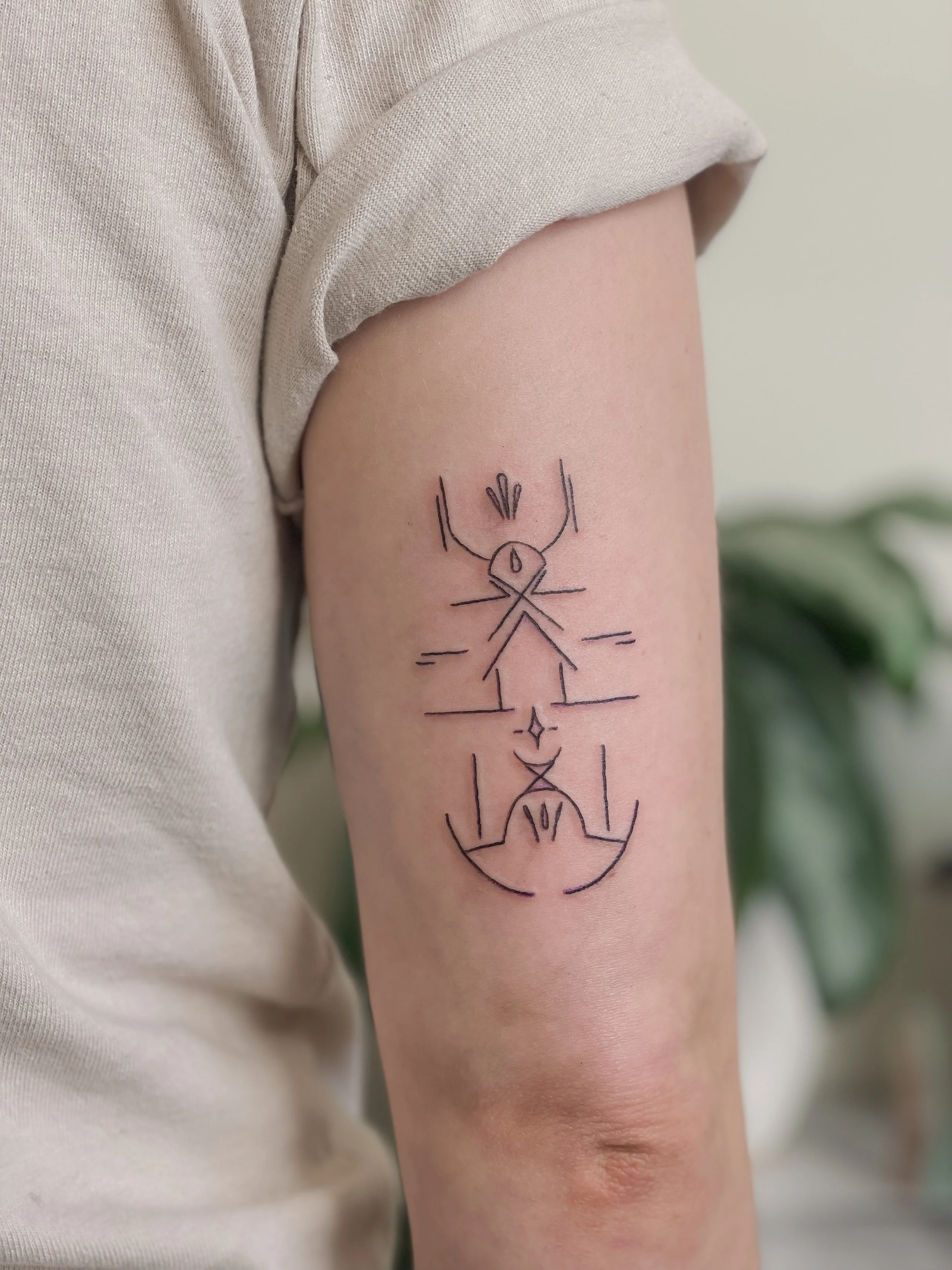 Tattoo of abstract line art on person's upper arm, featuring symmetrical geometric shapes, lines, and small decorative elements.