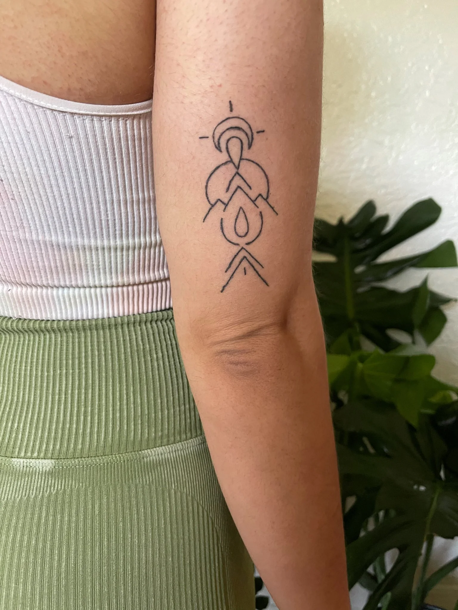 A tattoo on a person's upper arm featuring a geometric and abstract design with lines and shapes.