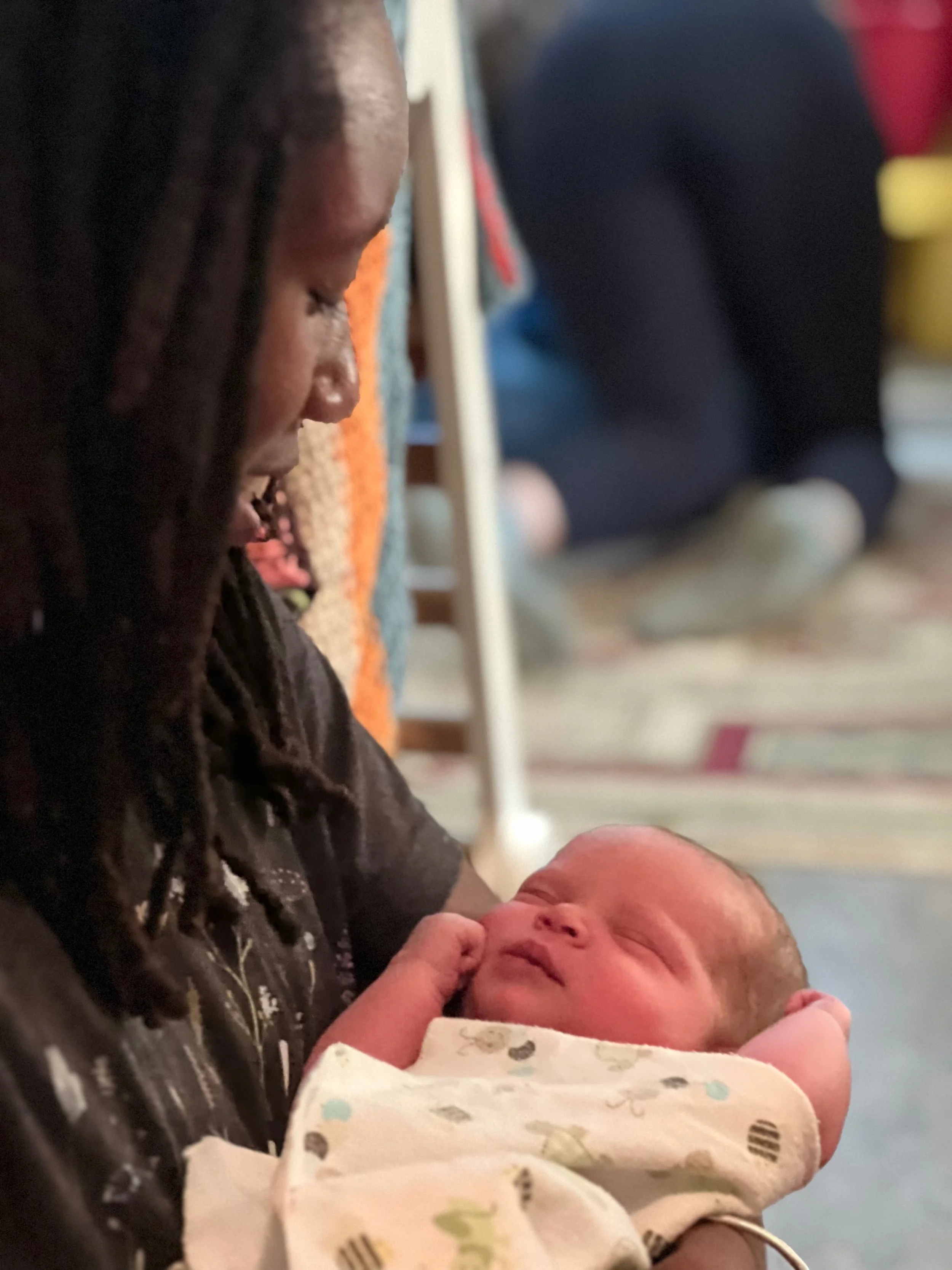 Person holding newborn baby, looking at it lovingly with a soft expression.