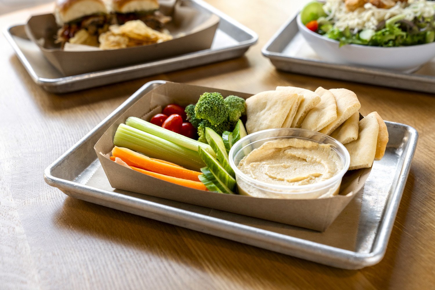 Vegetable platter with celery, cherry tomatoes, broccoli, cucumber, carrots, pita bread, and hummus