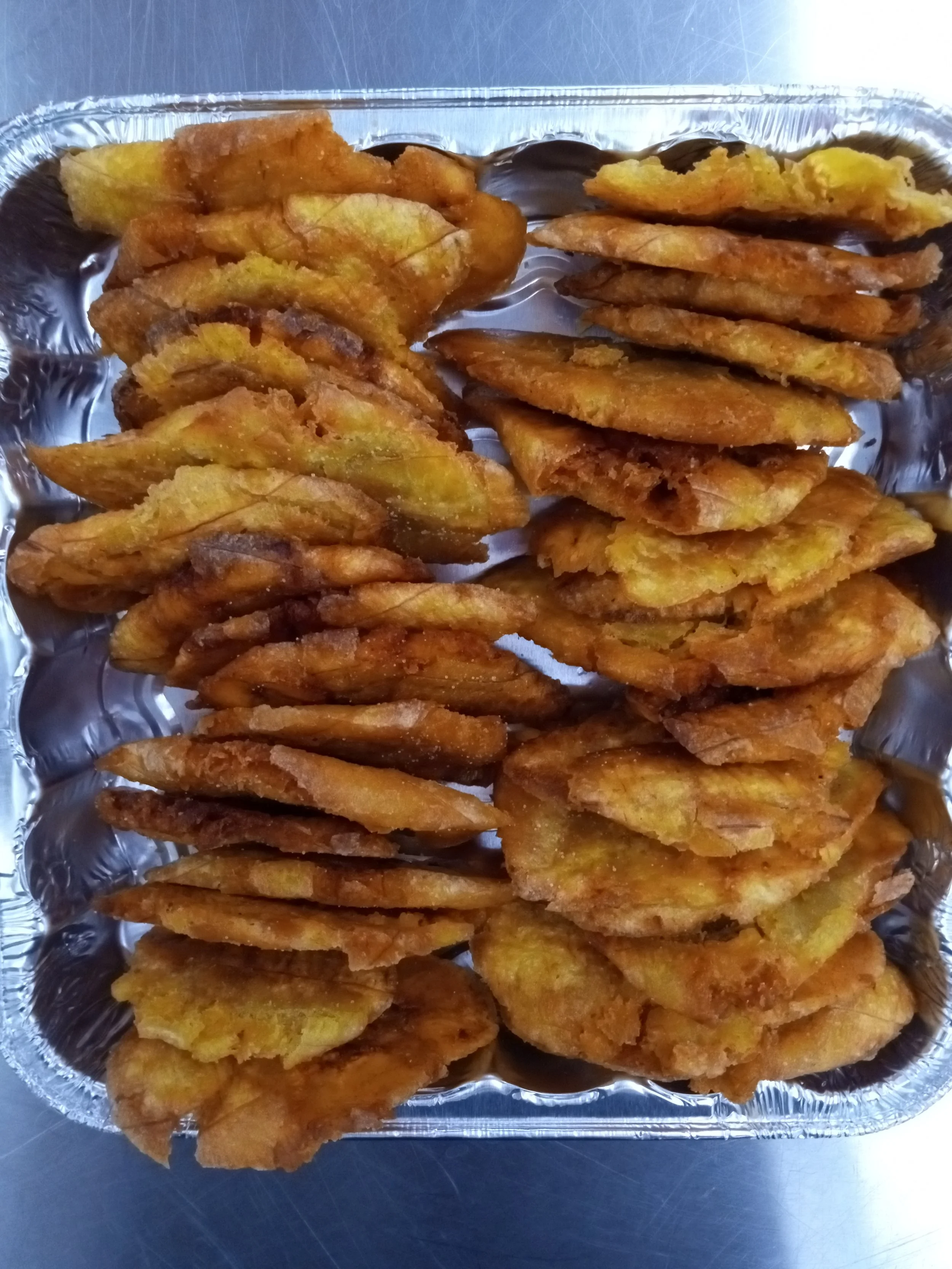 Fried plantains on a foil tray.