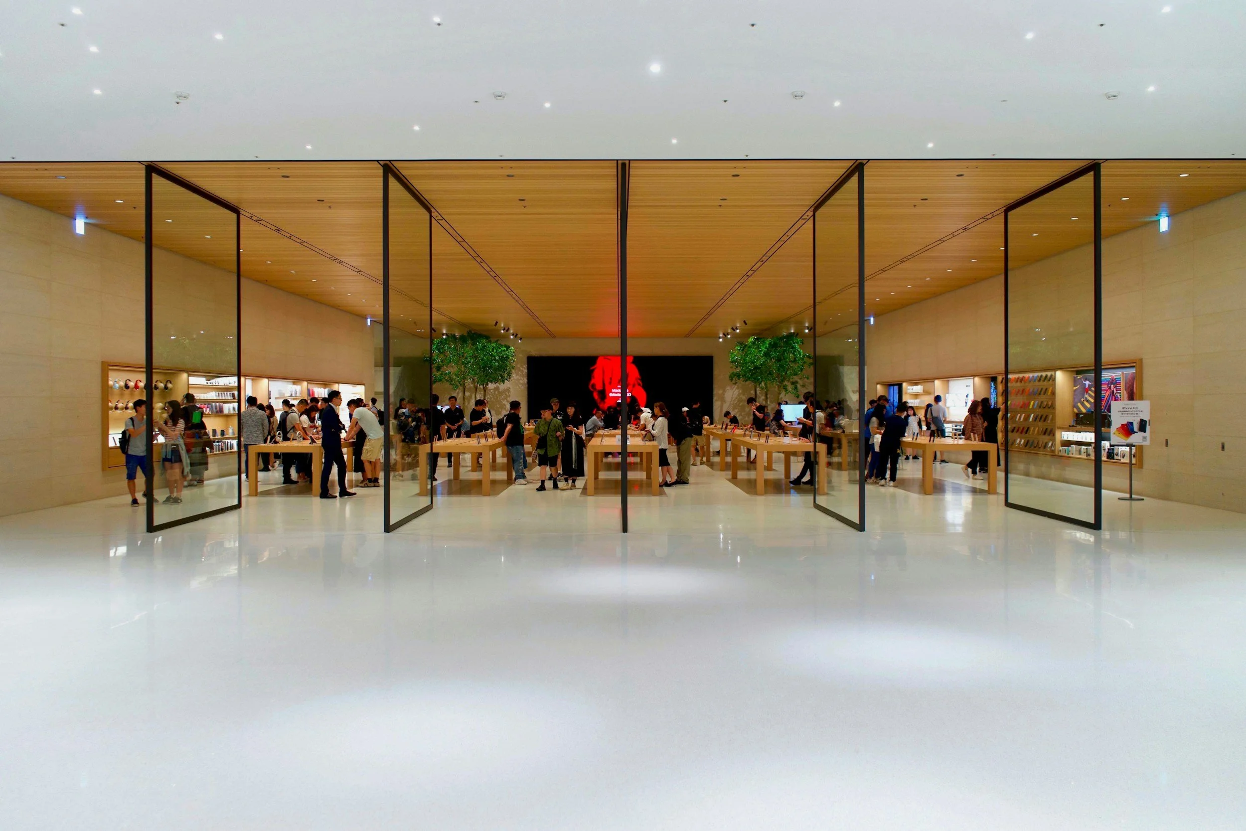 Interior of an Apple Store with people shopping and browsing products on display tables.