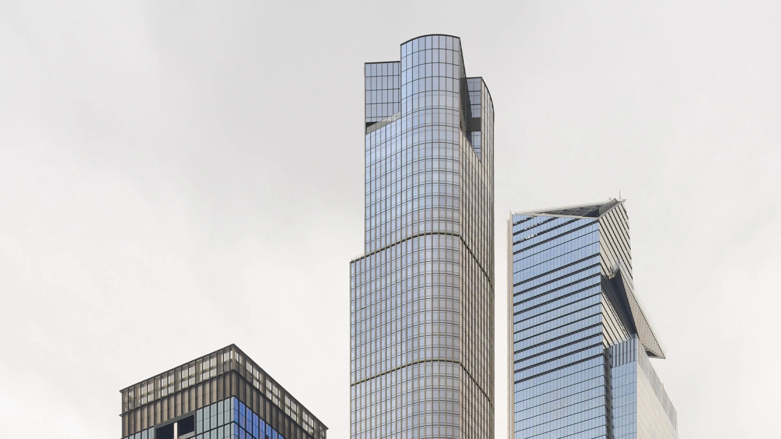 Three modern high-rise glass buildings against a cloudy sky.