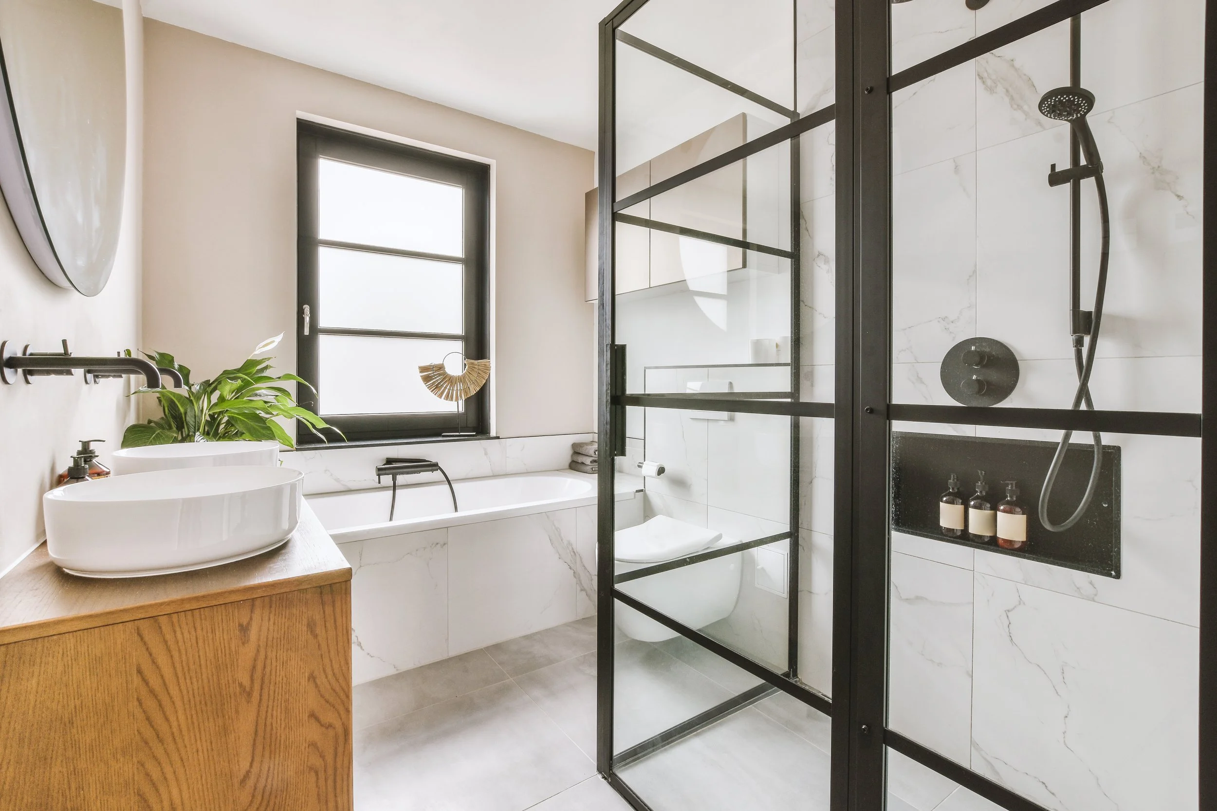 Modern bathroom with glass shower, freestanding tub, and wooden vanity.