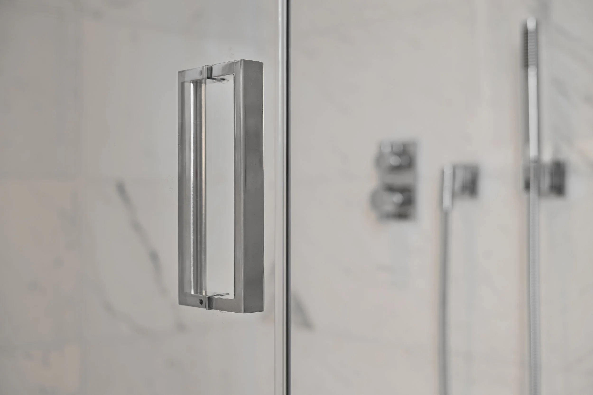 Close-up of a silver metal locker door handle with a keyhole, set against a light-colored wall with other blurred lockers in the background.