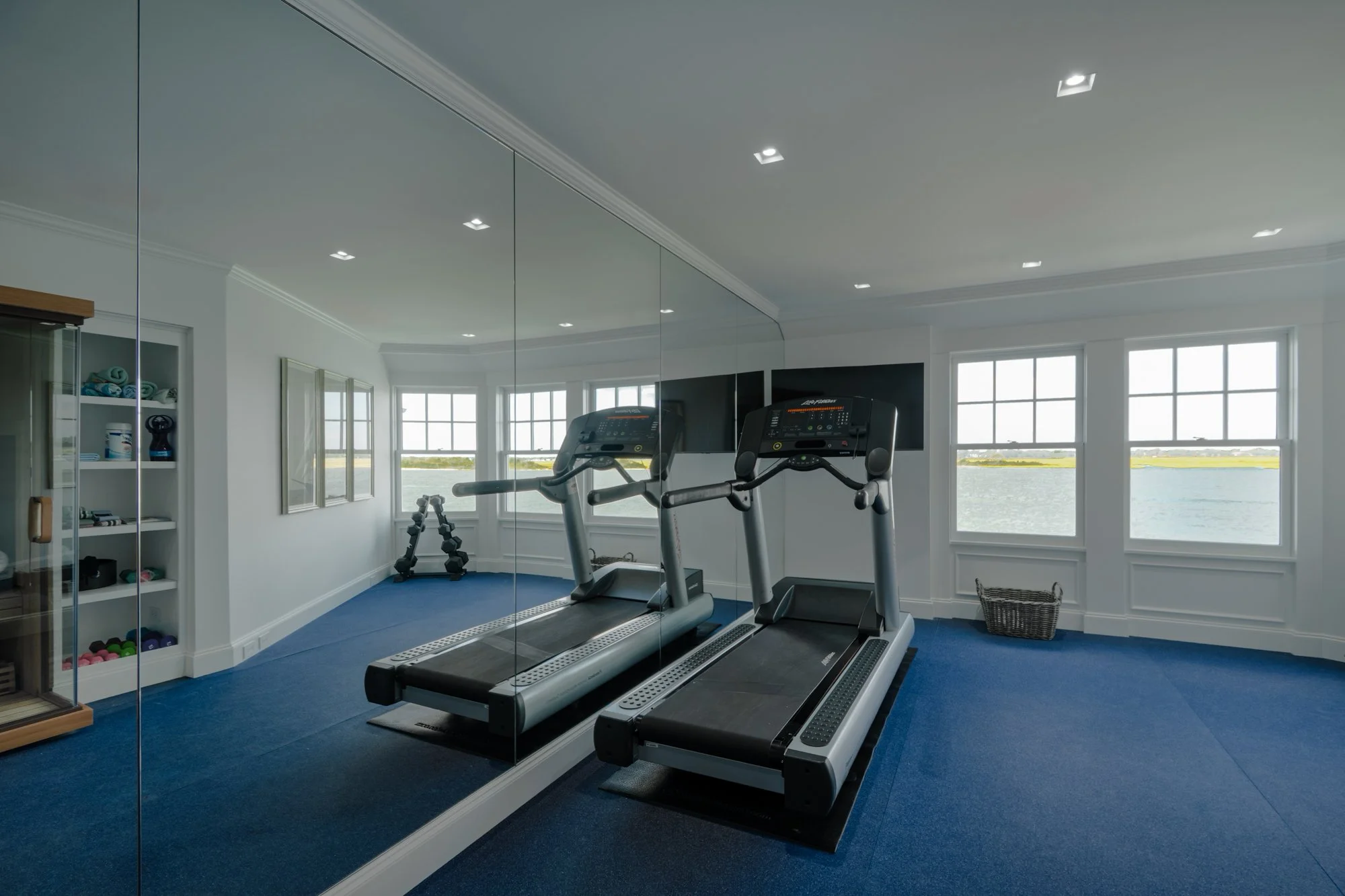 Modern gym interior with treadmills, exercise machines, and unique ceiling design.