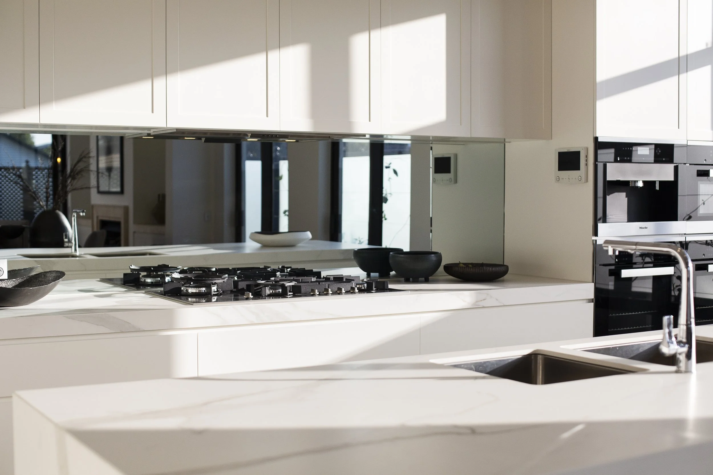 Modern kitchen with marble countertops, built-in gas stove, stainless steel sink, and black appliances.