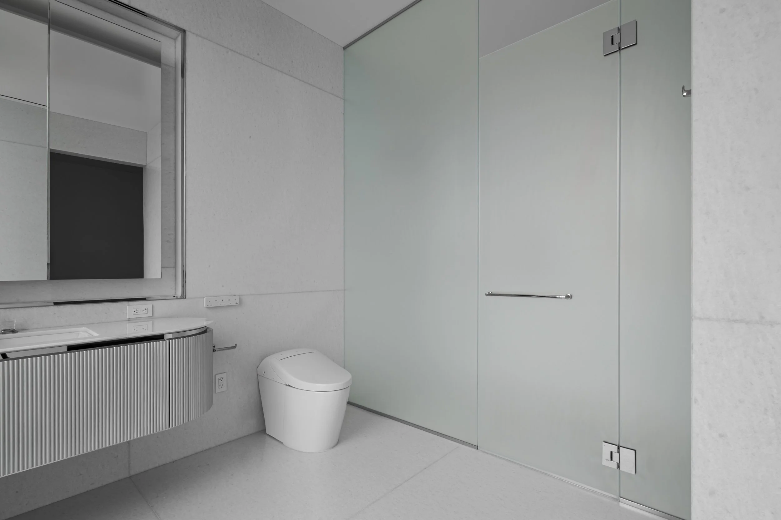 Modern bathroom with a freestanding bathtub, glass-enclosed shower, beige tile walls and floor, and a white bathrobe hanging.