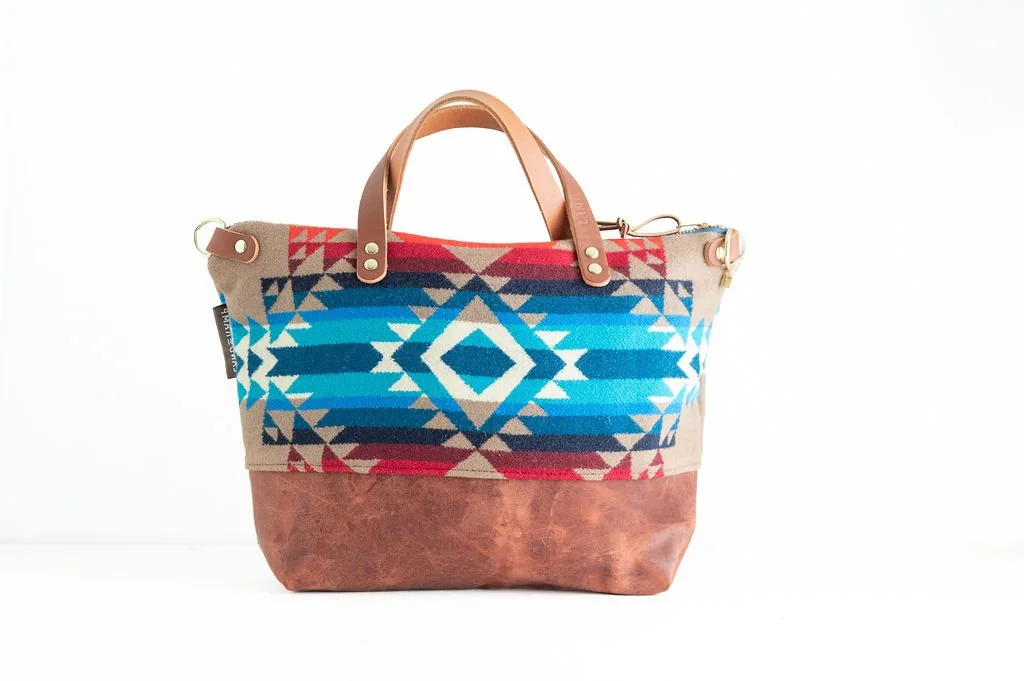 backside of pattern Handmade Pilot Rock wool crossbody purse with brown leather bottom and handles, crafted in Portland