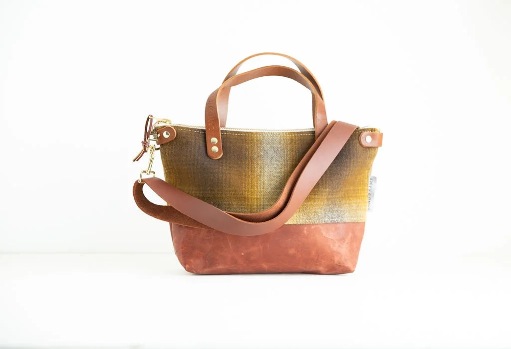 Detail view of the Wool Bitsy Crossbody Purse | Brown and Gold Ombre Plaid featuring YKK zipper and leather trim by Land & Kamp