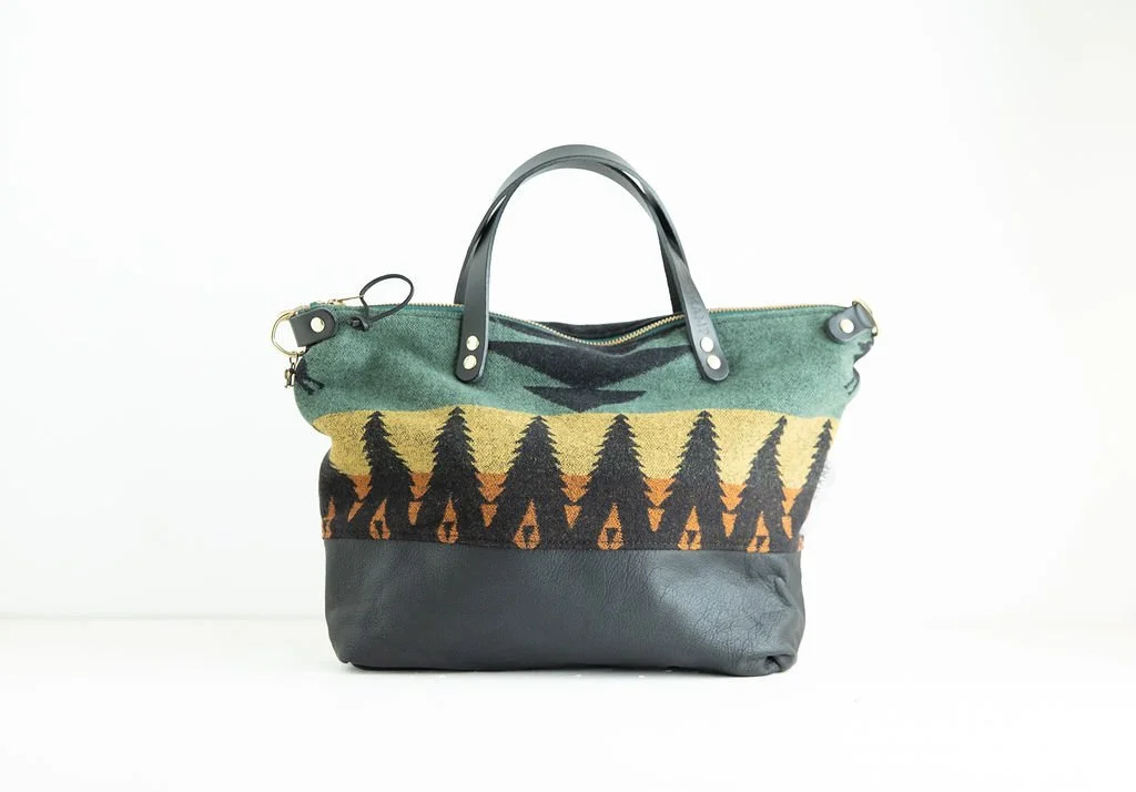 Handmade Tree Line wool crossbody purse with green wool, forest pattern, and black leather bottom, crafted in Portland