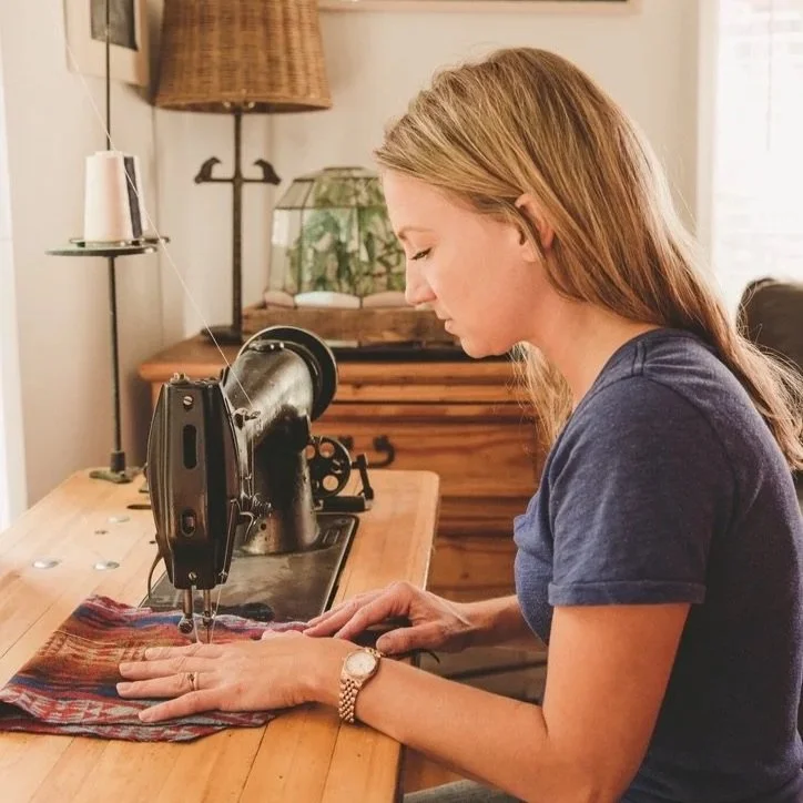 land and kamp owner jessie at a sewing machine sewing fabric