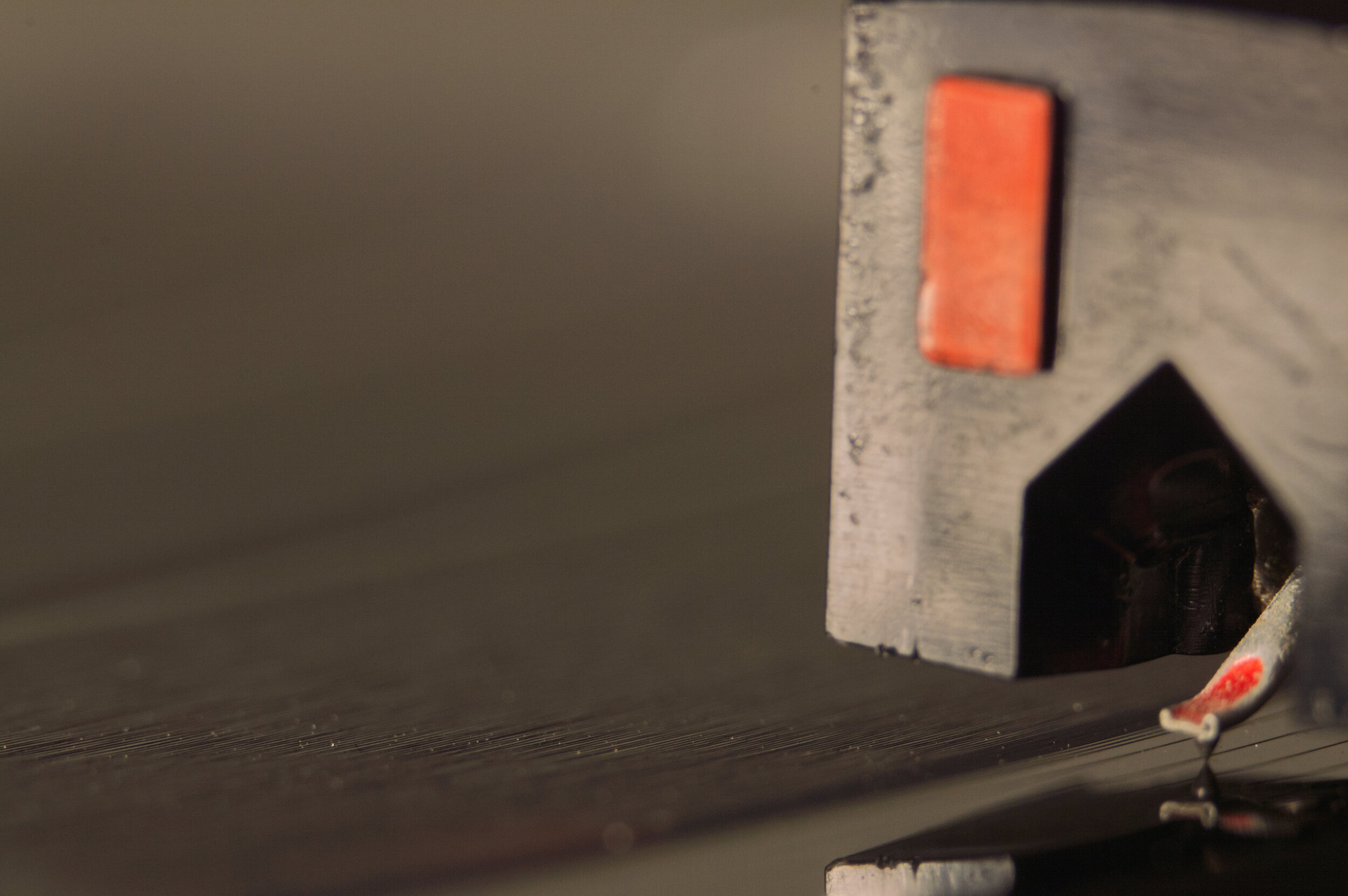 Close-up of a turntable stylus and cartridge on a vinyl record.