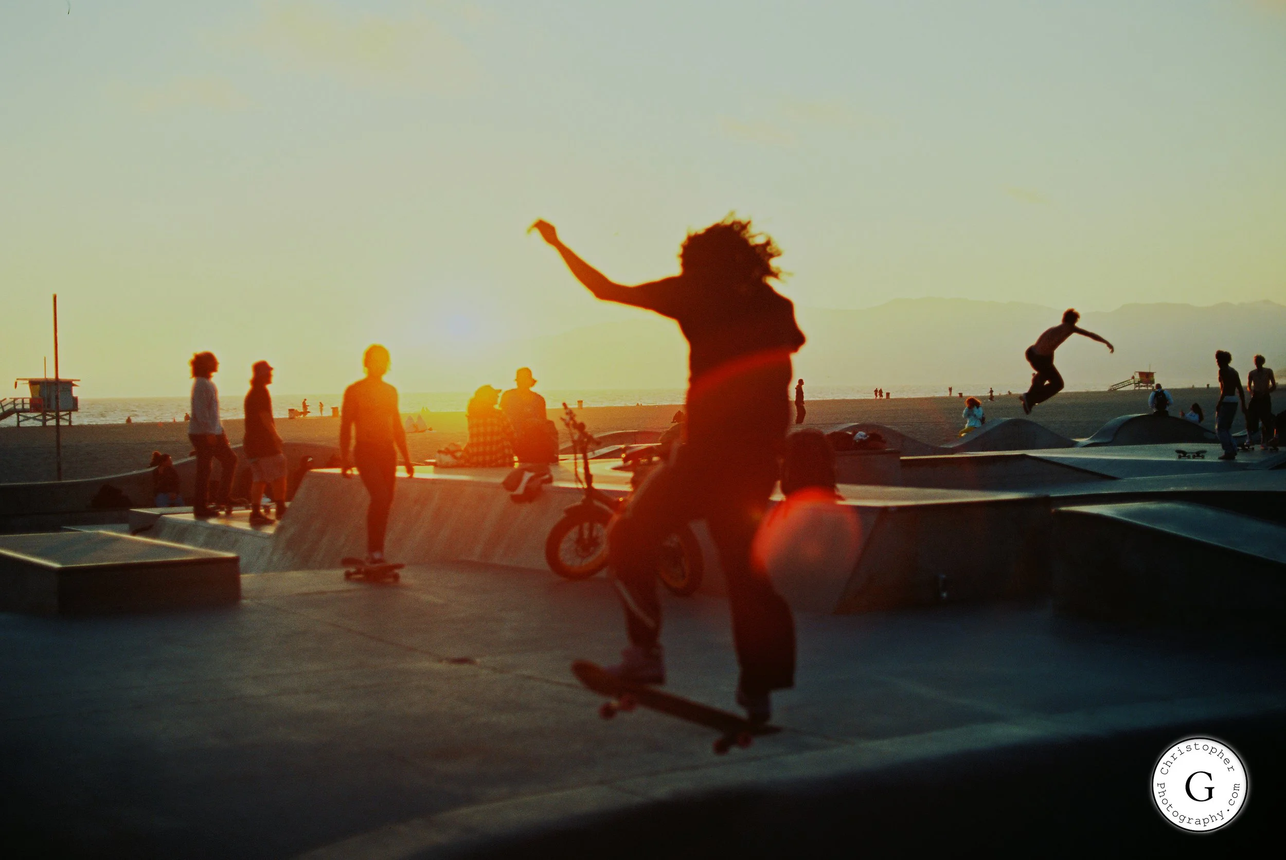 Silhouettes of people skateboarding and relaxing at Venice Beach during sunset shot on 35mm film.