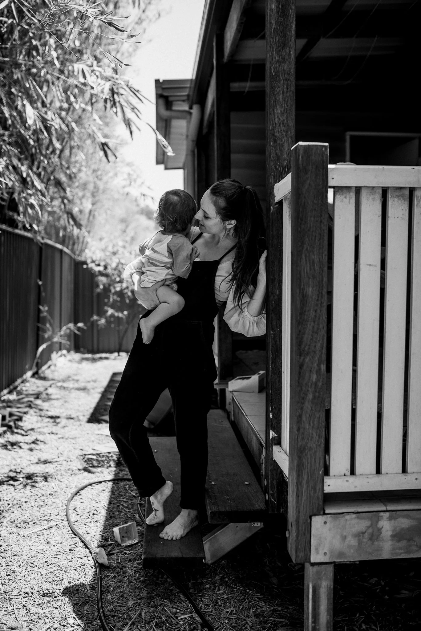 Black and white photo of a woman holding a child on a porch