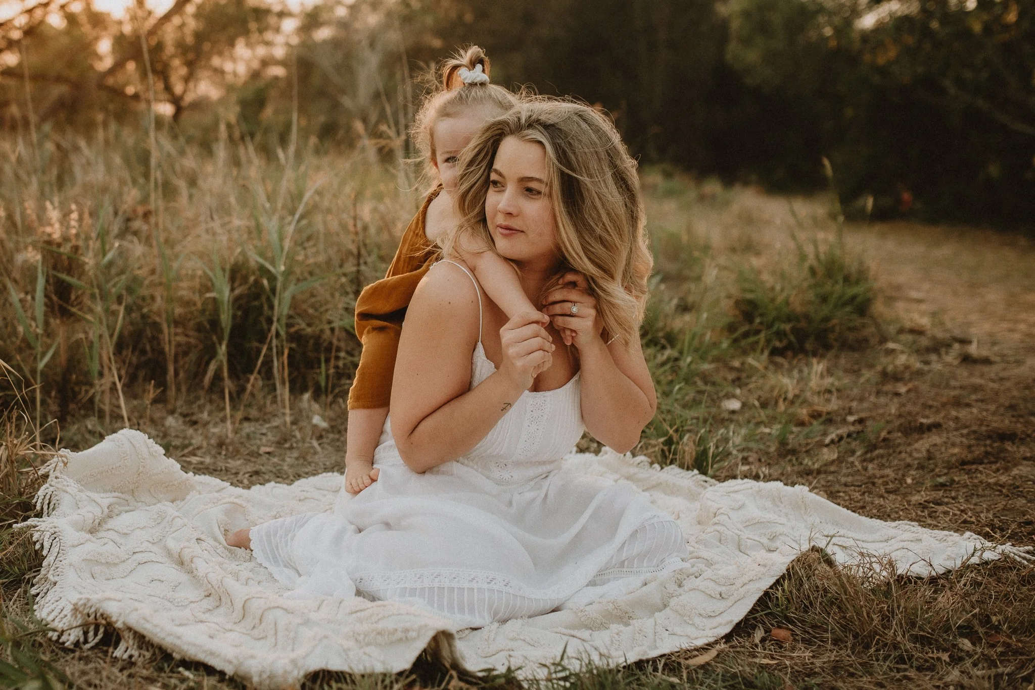 Woman sitting on blanket with child outdoors
