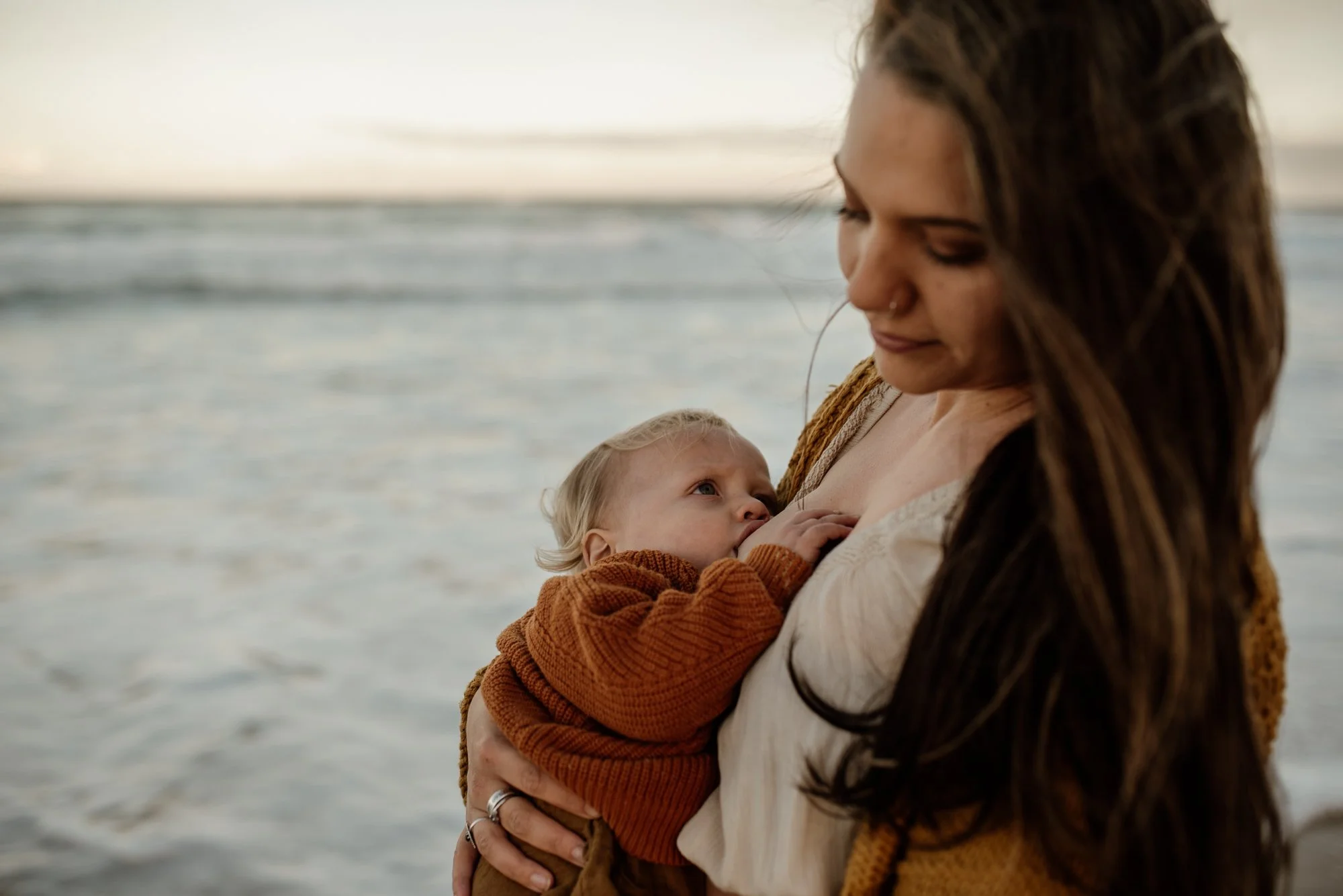 Woman breastfeeding her baby by the sea.