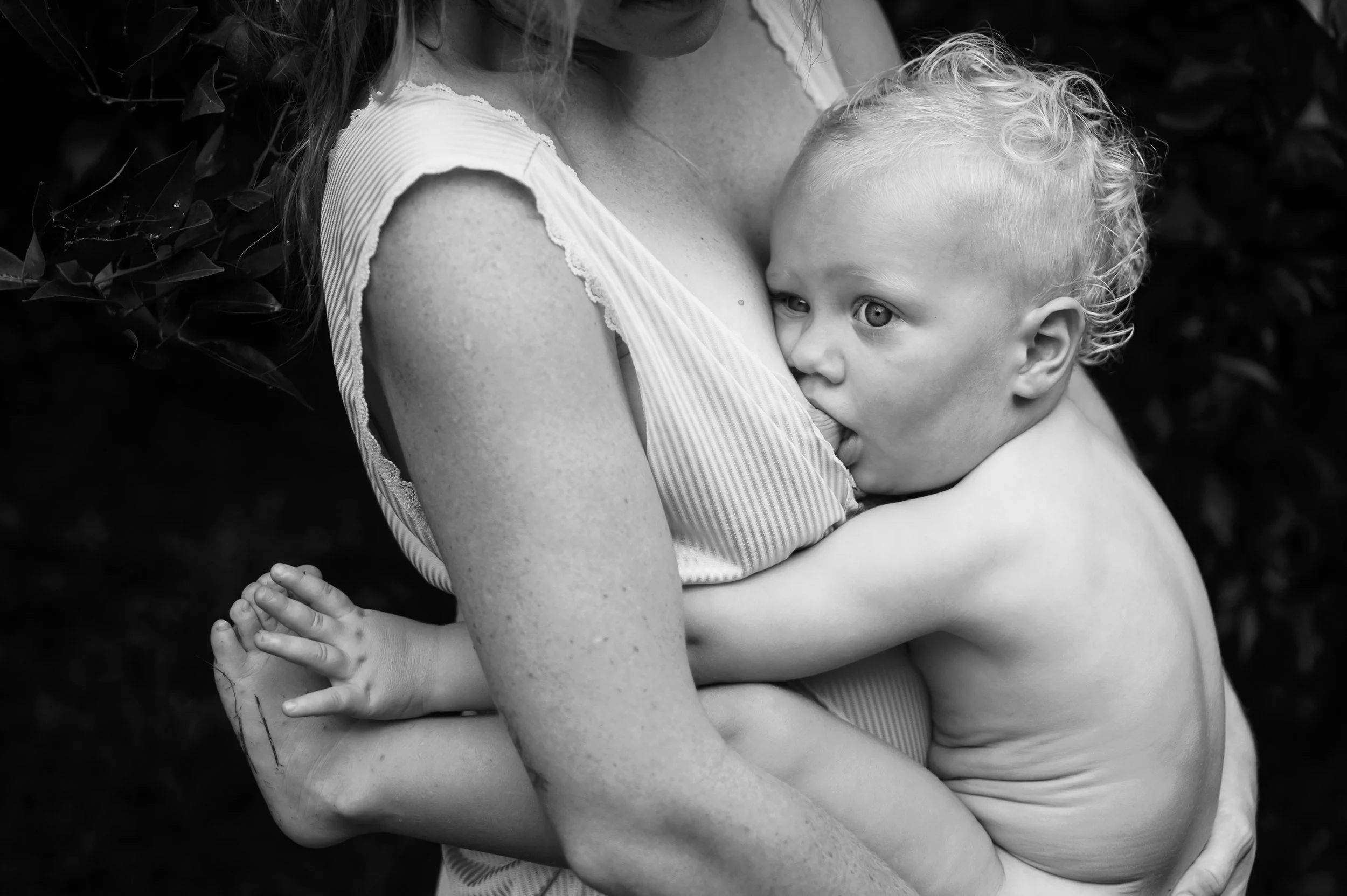 Black and white photo of a person breastfeeding a child.