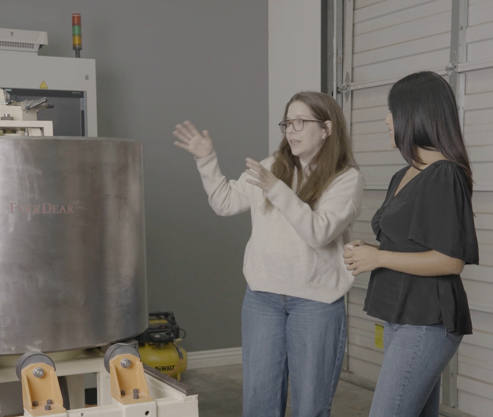 Two people talking beside diamond growing equipment marked EverDear in a research lab.