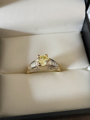 A stunning yellow diamond memorial ring set in gold, accented with sparkling baguette diamonds along the band.