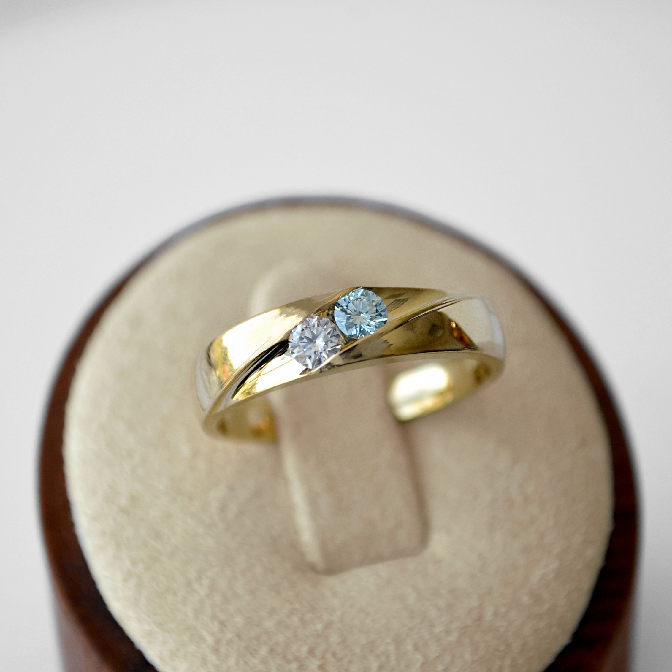 A classic yellow gold cremation ring with delicate blue diamond and colorless diamond, set simply yet elegantly for a subtle tribute.