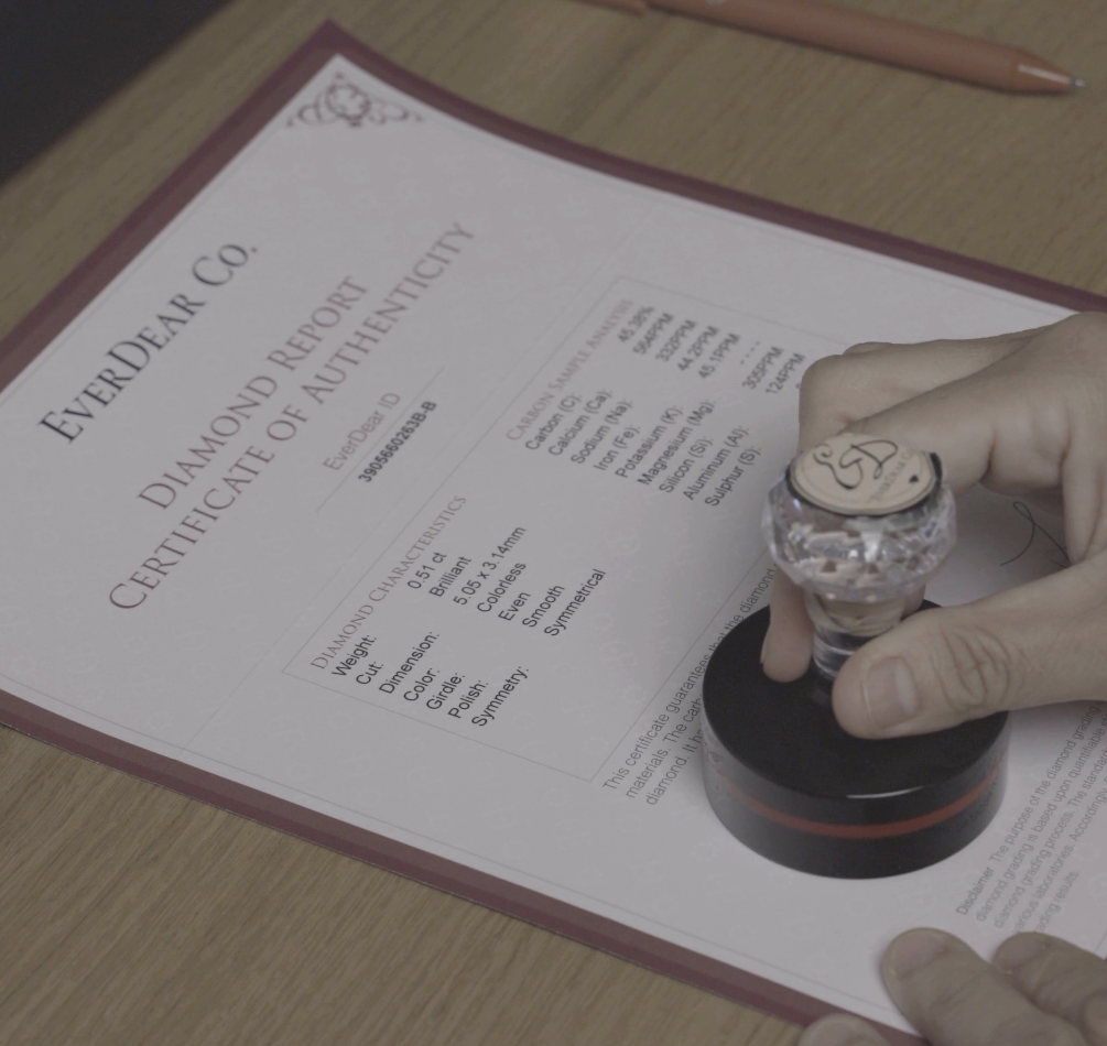 A hand stamping an EverDear Certificate of Authenticity showing diamond characteristics and a carbon sample analysis