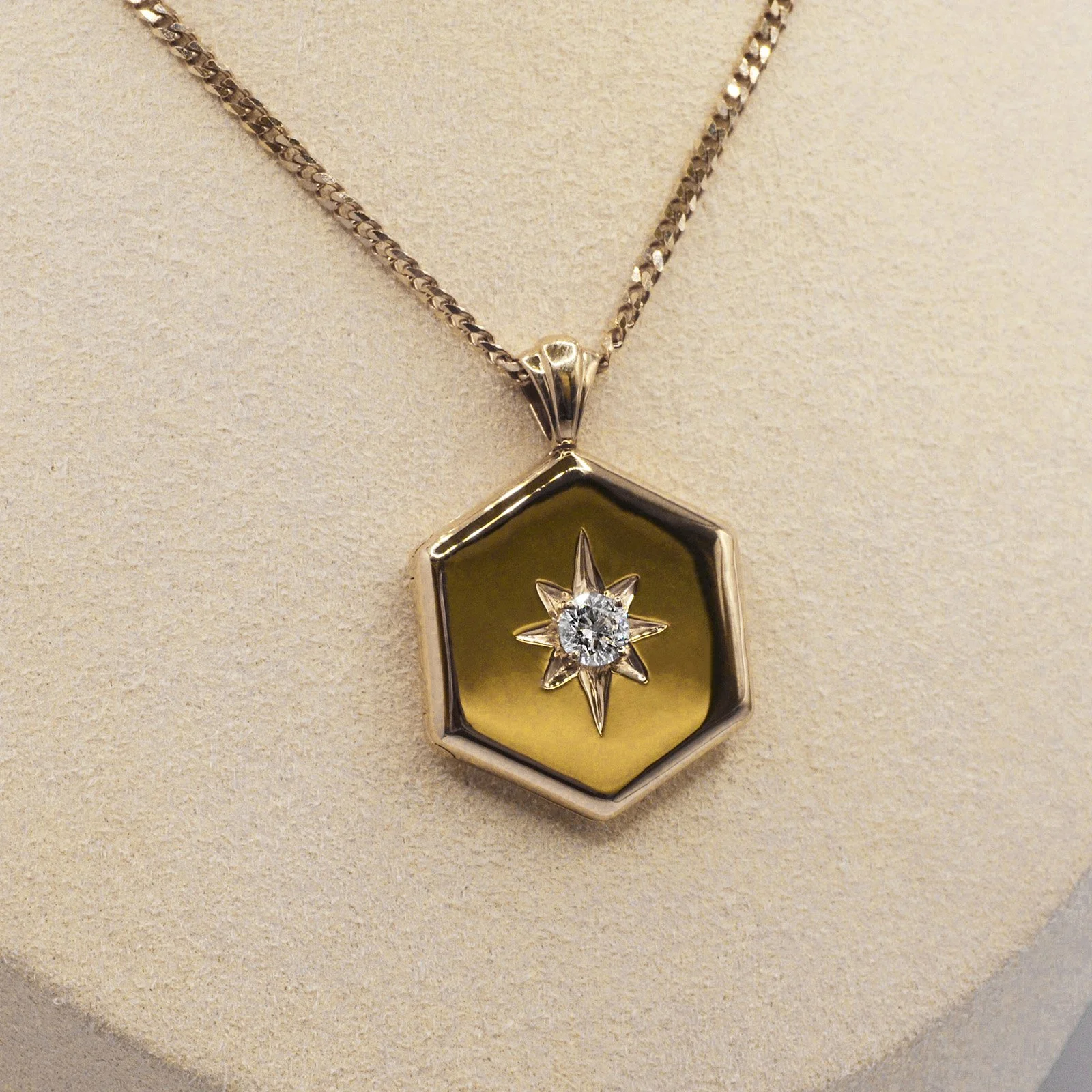 Hexagon-shaped gold locket with a radiant starburst design, centered by a brilliant cremation diamond. This EverDear memorial locket opens to hold cherished memories, symbolizing eternal love and connection, crafted from ashes or hair.