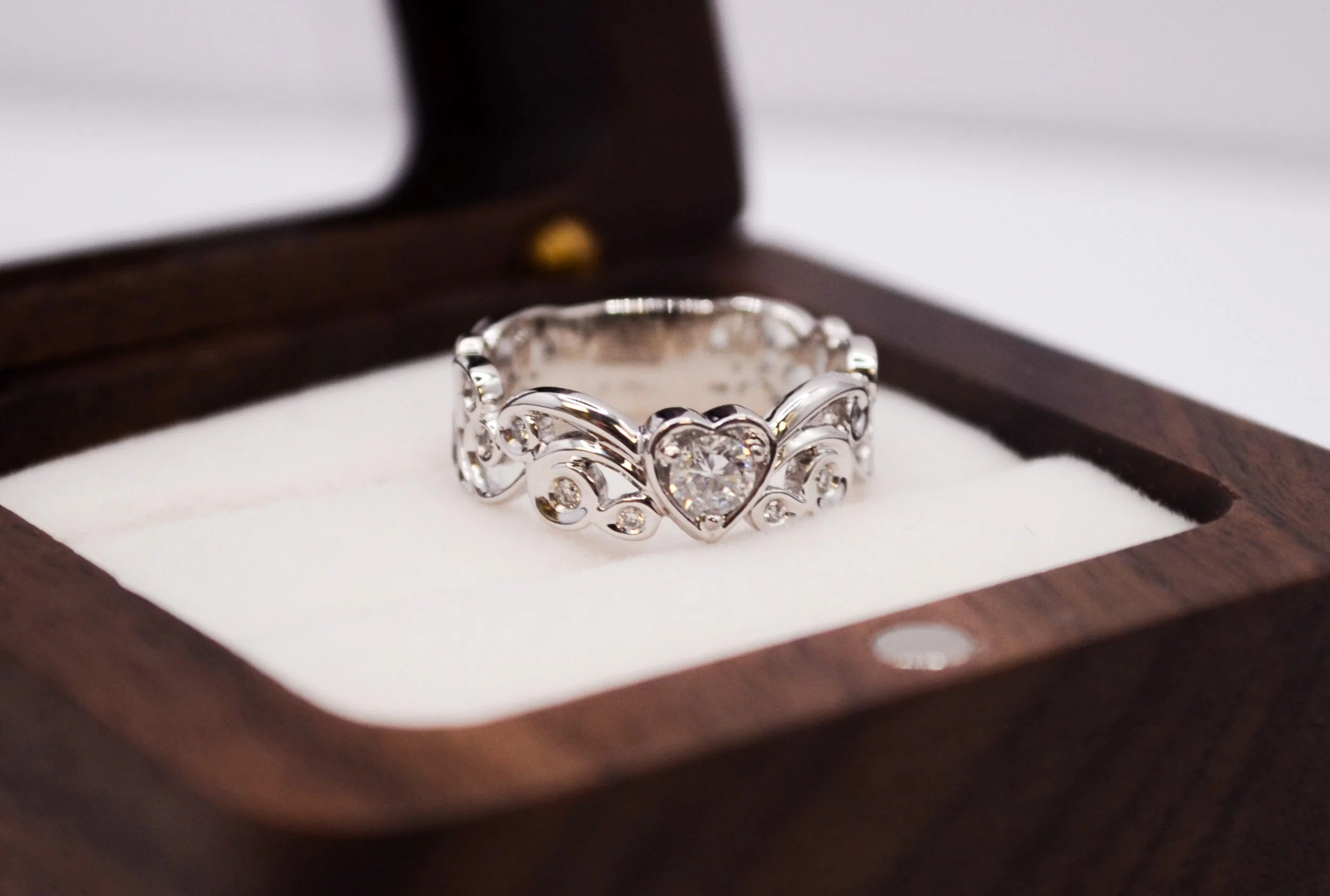 White gold ring with an intricate filigree design, featuring a heart-shaped white cremation diamond at its center, symbolizing eternal love and crafted by EverDear.