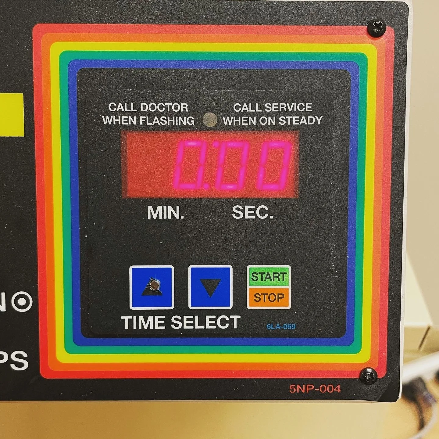 A digital timer with a rainbow-colored border, displaying 0:00, with buttons for time selection and start/stop functions.