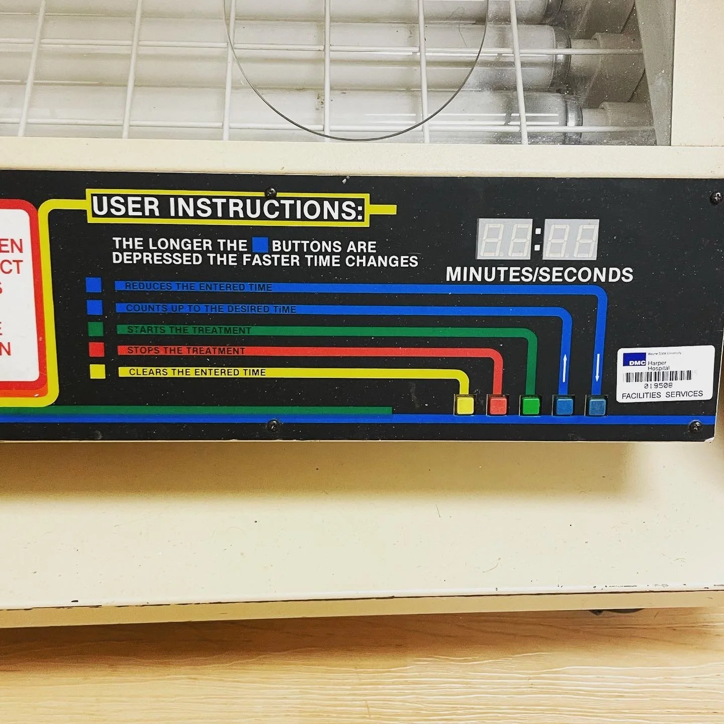 A medical device panel with labeled colored buttons for adjusting treatment time, included are instructions on button functions and a digital timer display.