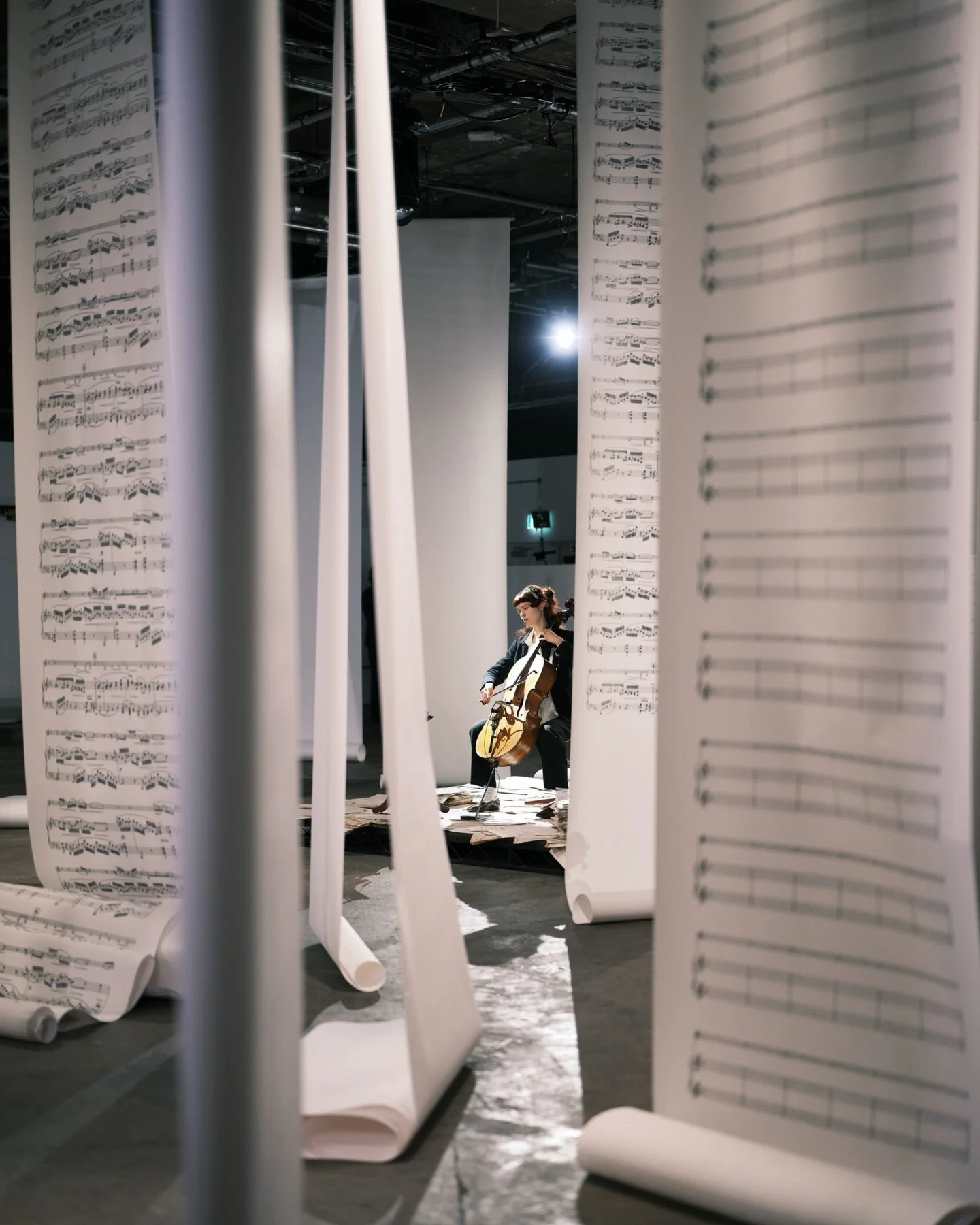 Production poetry at its finest with @the_ouze five-meter music sheets cascading from the rig to form a paper forest, columns of stacked paper transforming into plinths for jewellery, and a lone cellist elevated at the centre, playing dramatic chords