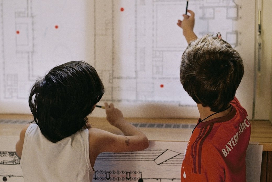 Two children standing in front of building plans in the Bauakademie.