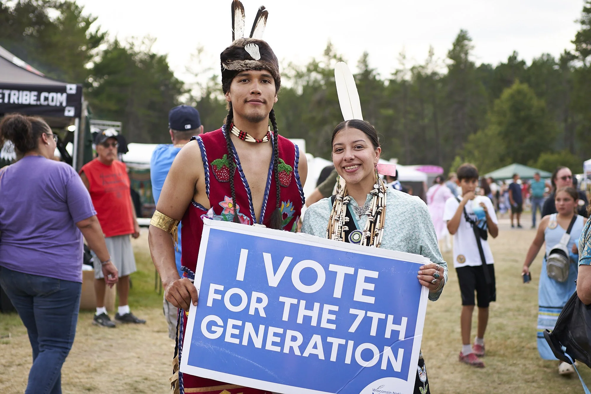 two people in regalia holding I vote sign