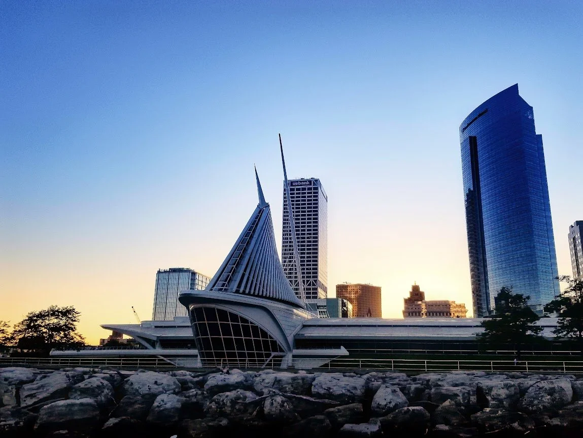 City skyline featuring a modern church building with pointed spires and surrounding high-rise buildings at sunset.