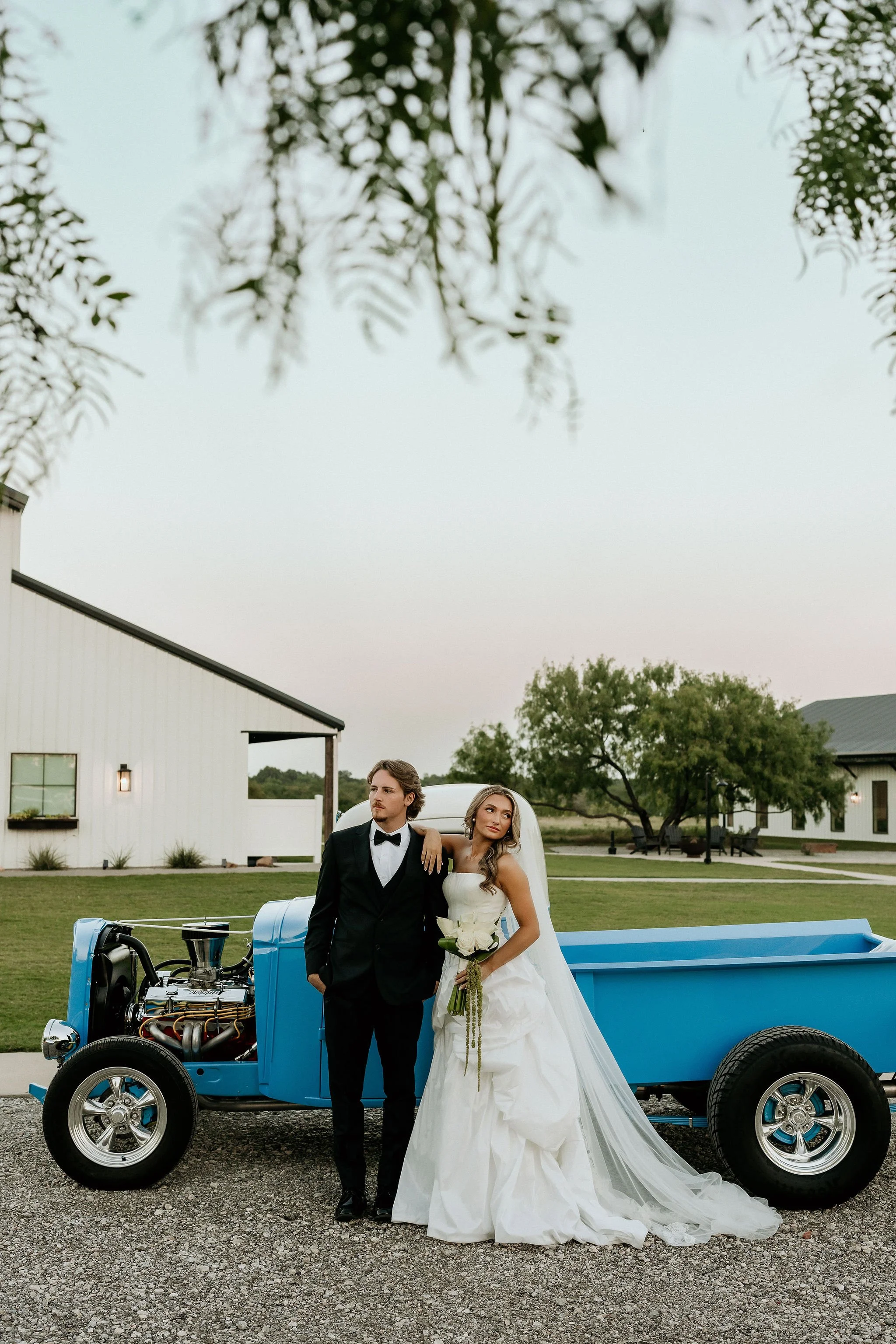 bride and groom with getaway car at white barn wedding