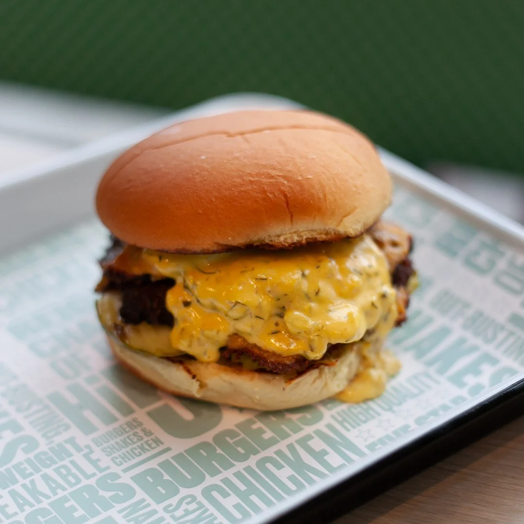Cheeseburger with melted cheese, a beef patty, lettuce, and a bun on a tray.