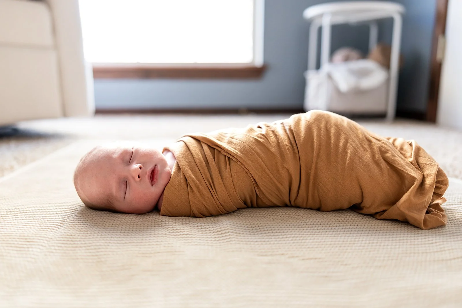 baby boy photorgaphed in nursey in his home near canyon texas photographed by vanessa underwood photography a newborn and maternity photorgapher baby is wrapped in nutral yellow brown swaddle sleeping