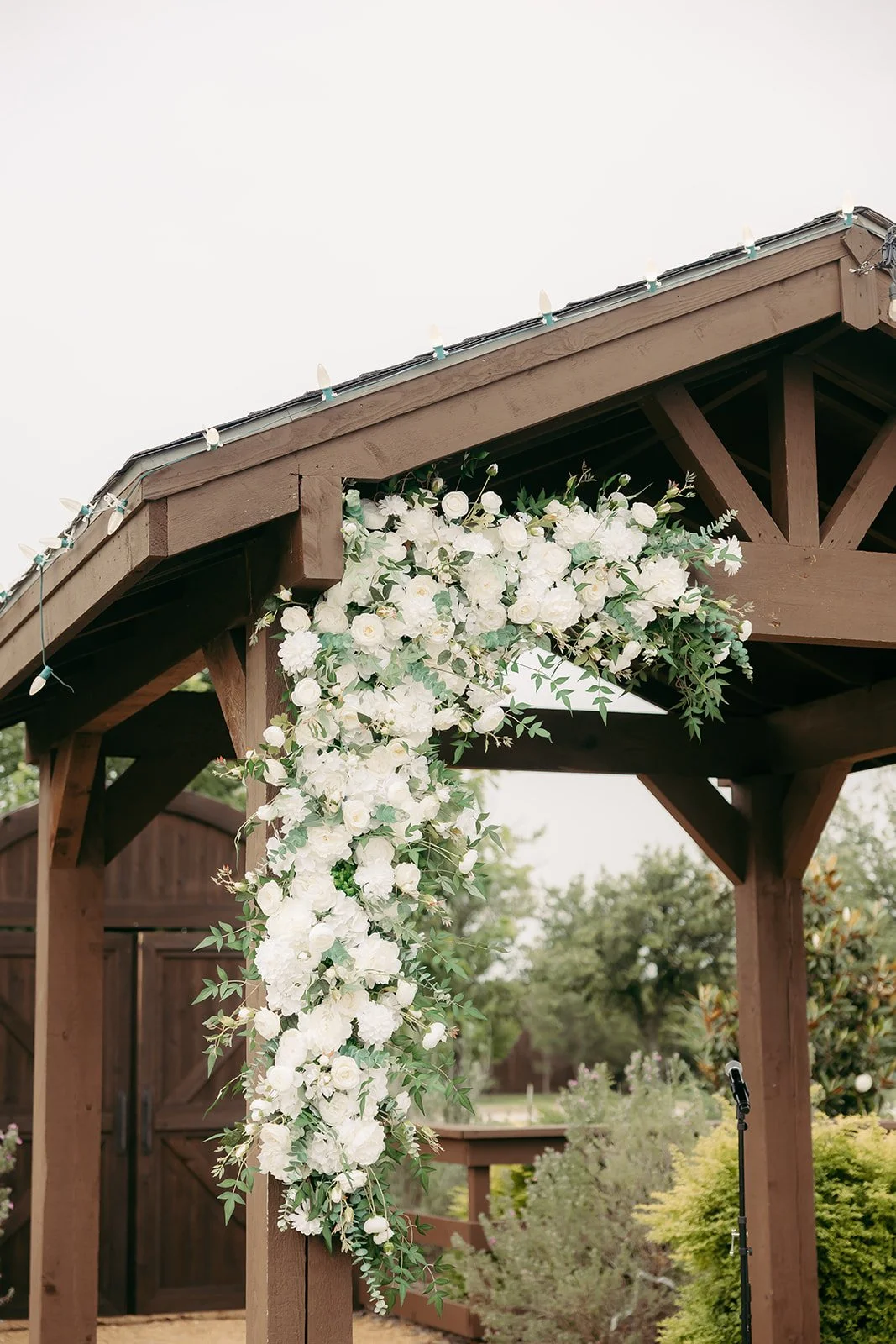 White flowers and greenery on the outdoor ceremony pavilion at The Melissa Barn