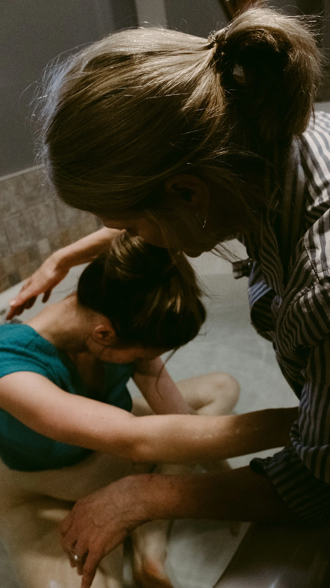 A woman supporting a young girl who appears to be having a medical emergency, possibly in a bathroom.
