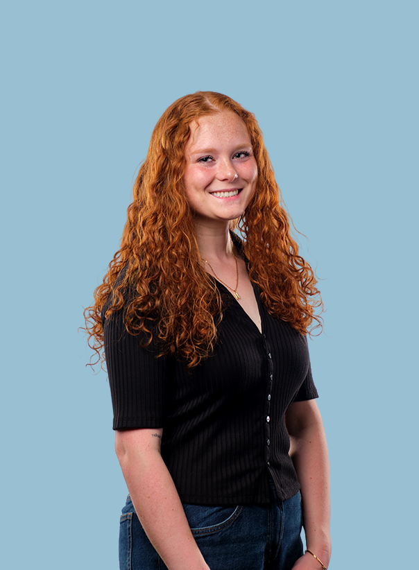 Headshot of Hailey, DMZ's social media manager and content creator, wearing a black button-up shirt, smiling, against a light blue background.