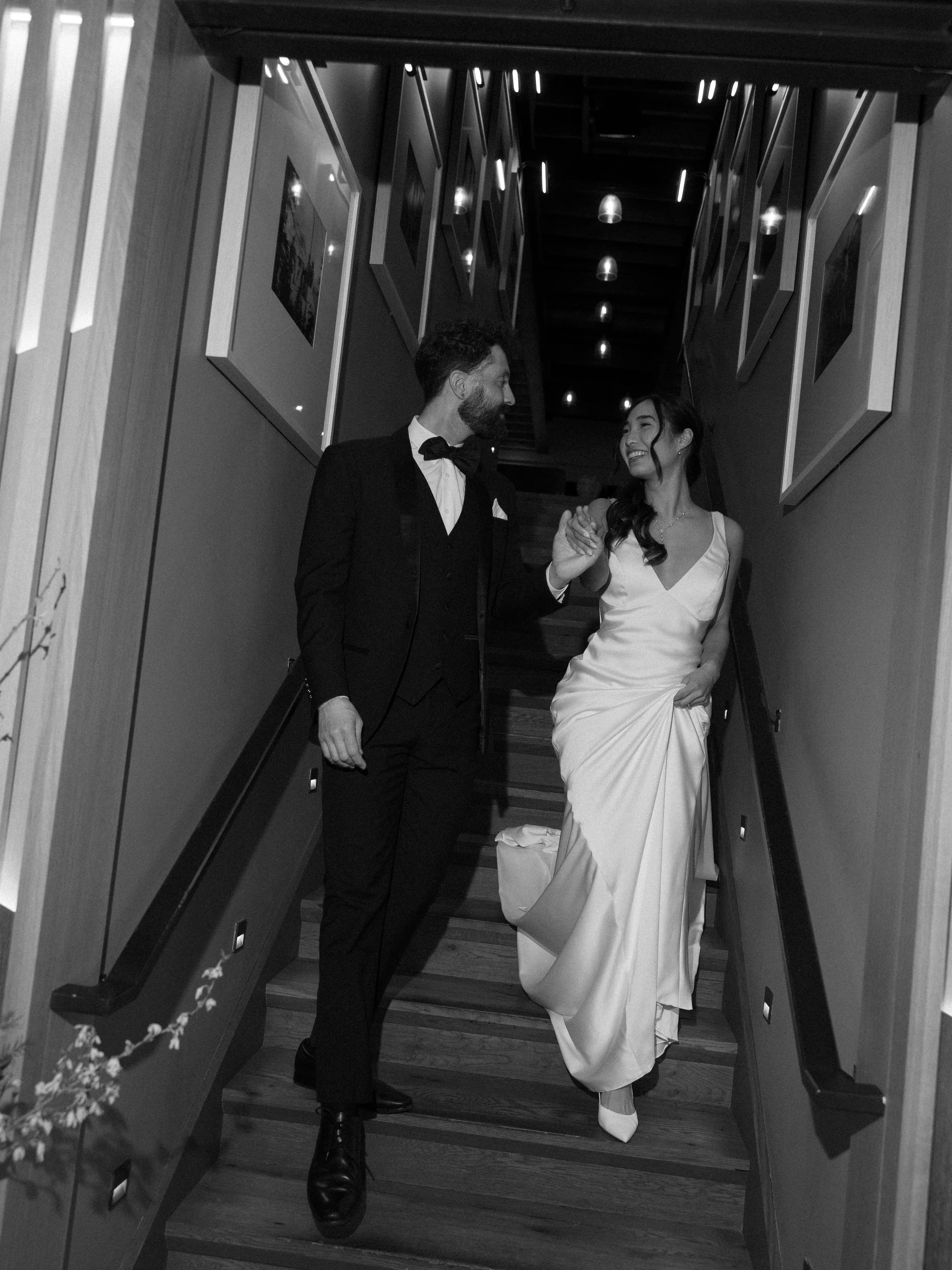 bride-holding-up-silk-gown-as-she-walks-down-stairs.jpg