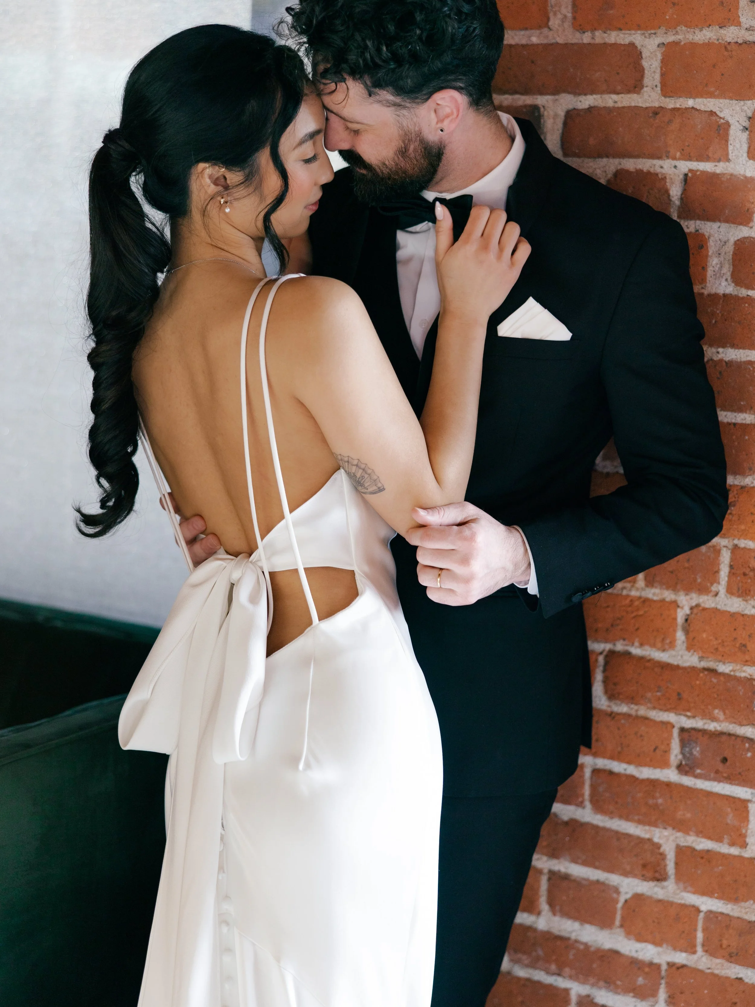 Bride-kissing-groom-against-brick-wall.jpg